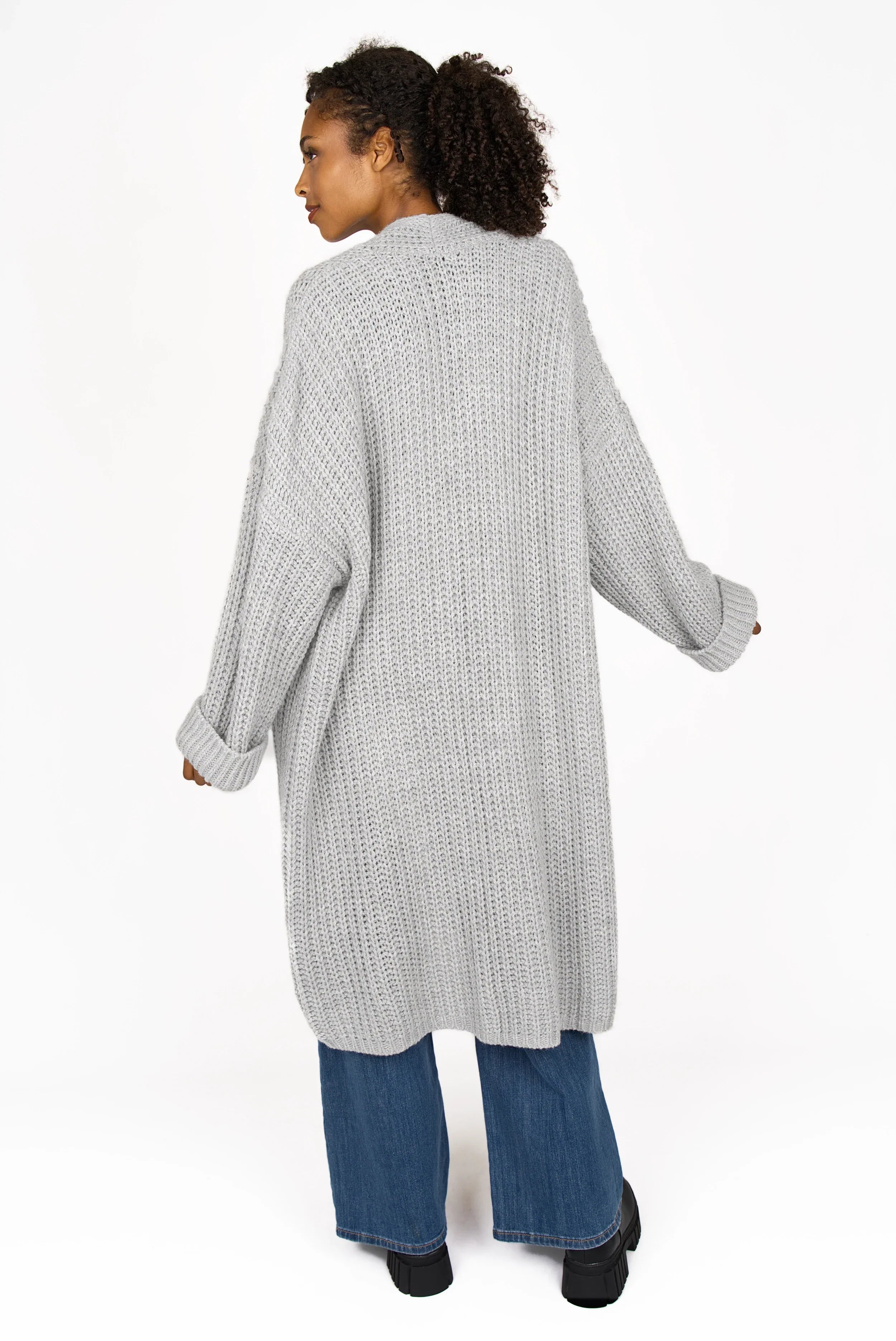 Frau trägt grauen oversized LOL Strickcardigan offen mit umgeschlagenen Ärmeln und Taschen