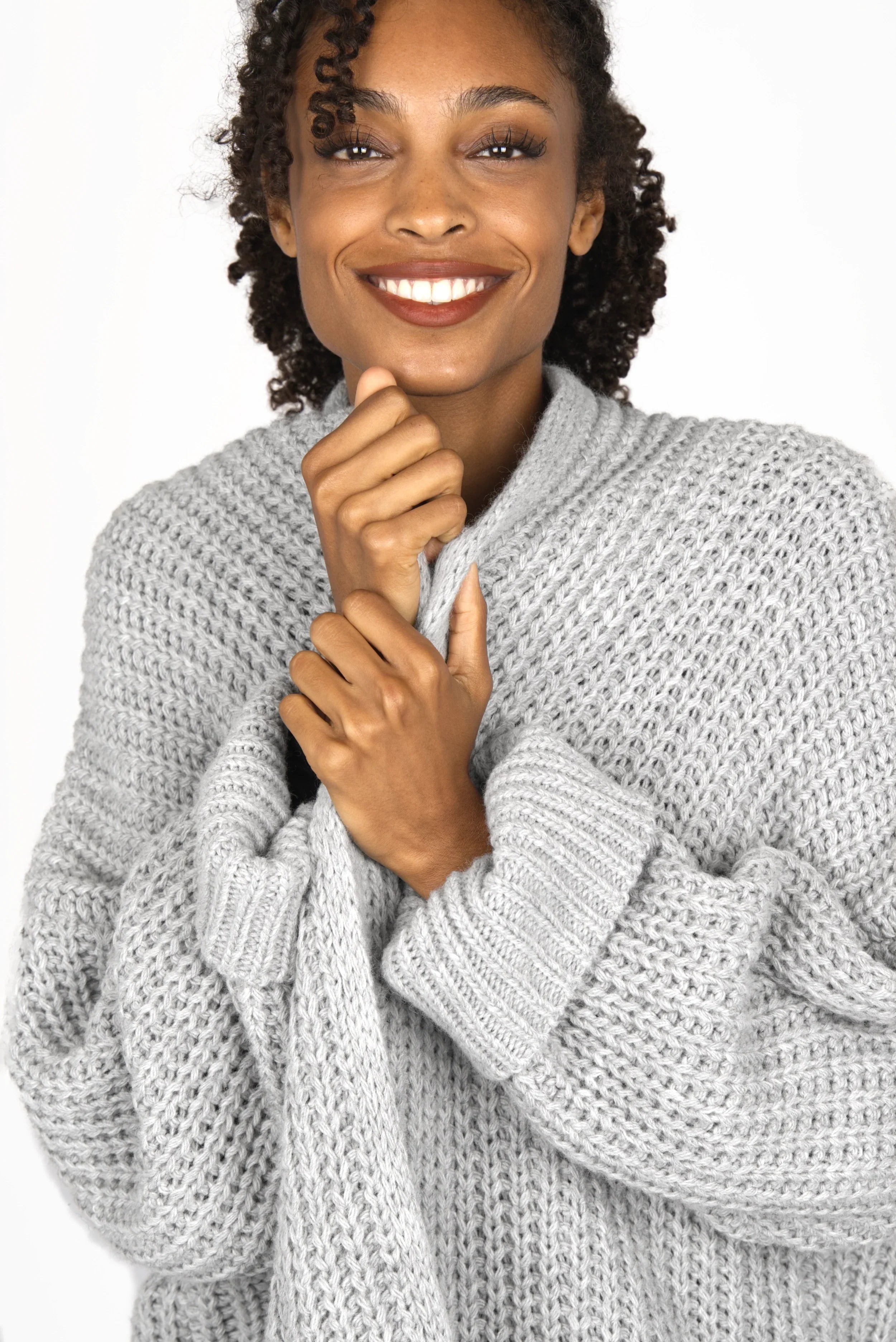 Frau trägt grauen oversized LOL Strickcardigan mit umgeschlagenen Ärmeln und offenem Schnitt