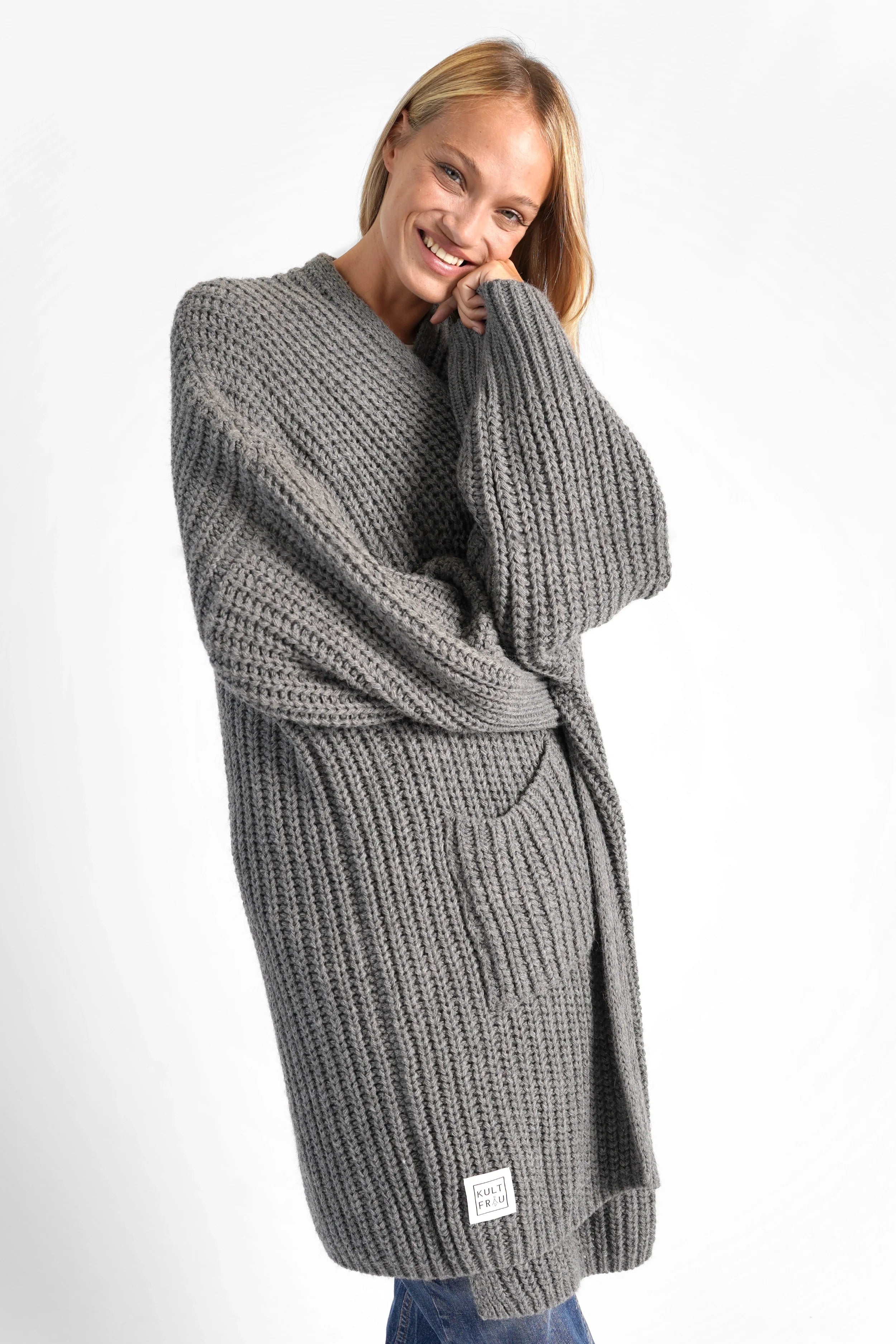 Frau trägt oversized grauen LOLLYTA Strickcardigan mit aufgesetzten Taschen und überschnittenen Schultern