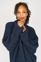 Frau trägt oversized dunkelblauen Strickcardigan mit überschnittenen Schultern und aufgesetzten Taschen
