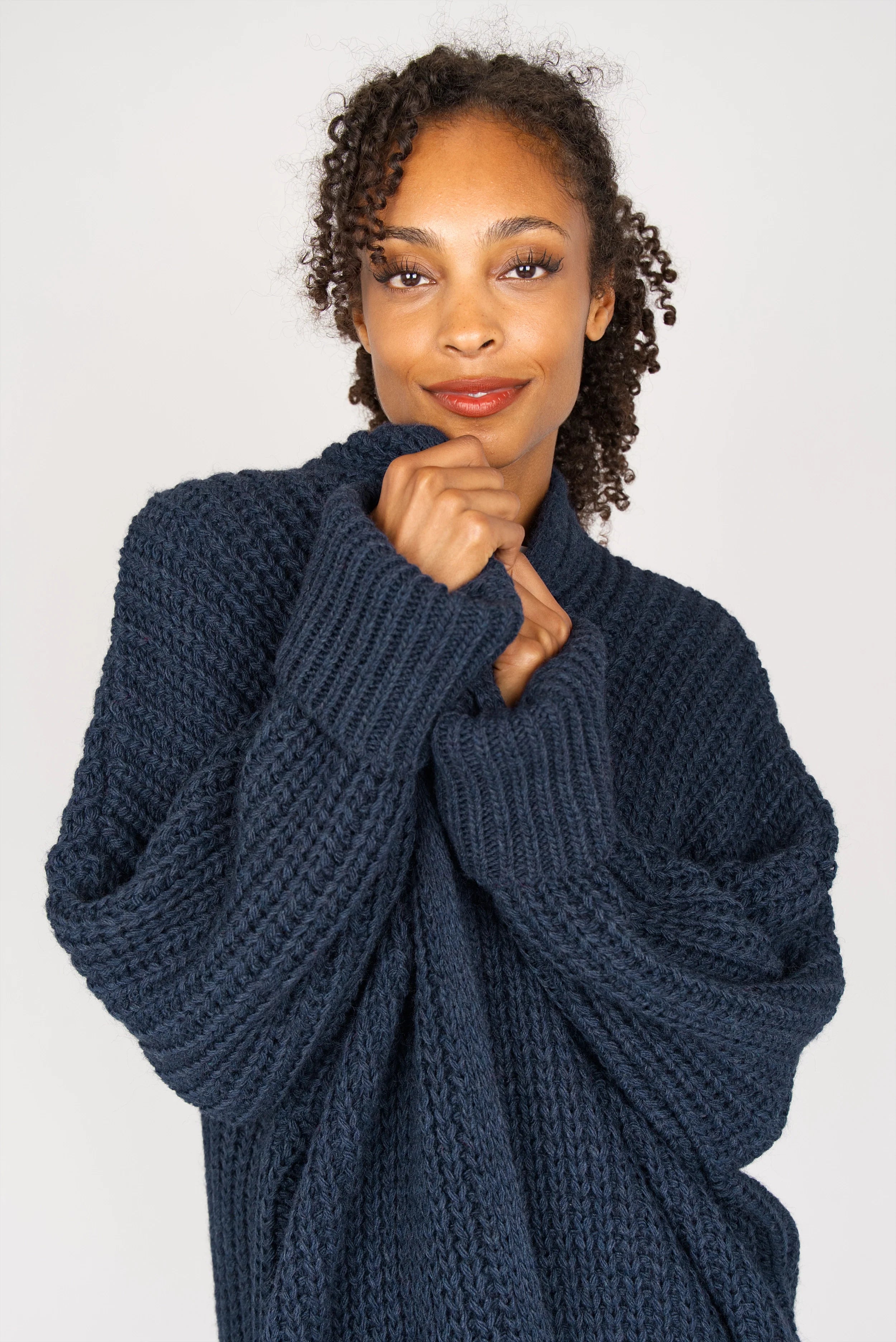 Frau trägt oversized dunkelblauen Strickcardigan mit überschnittenen Schultern und aufgesetzten Taschen