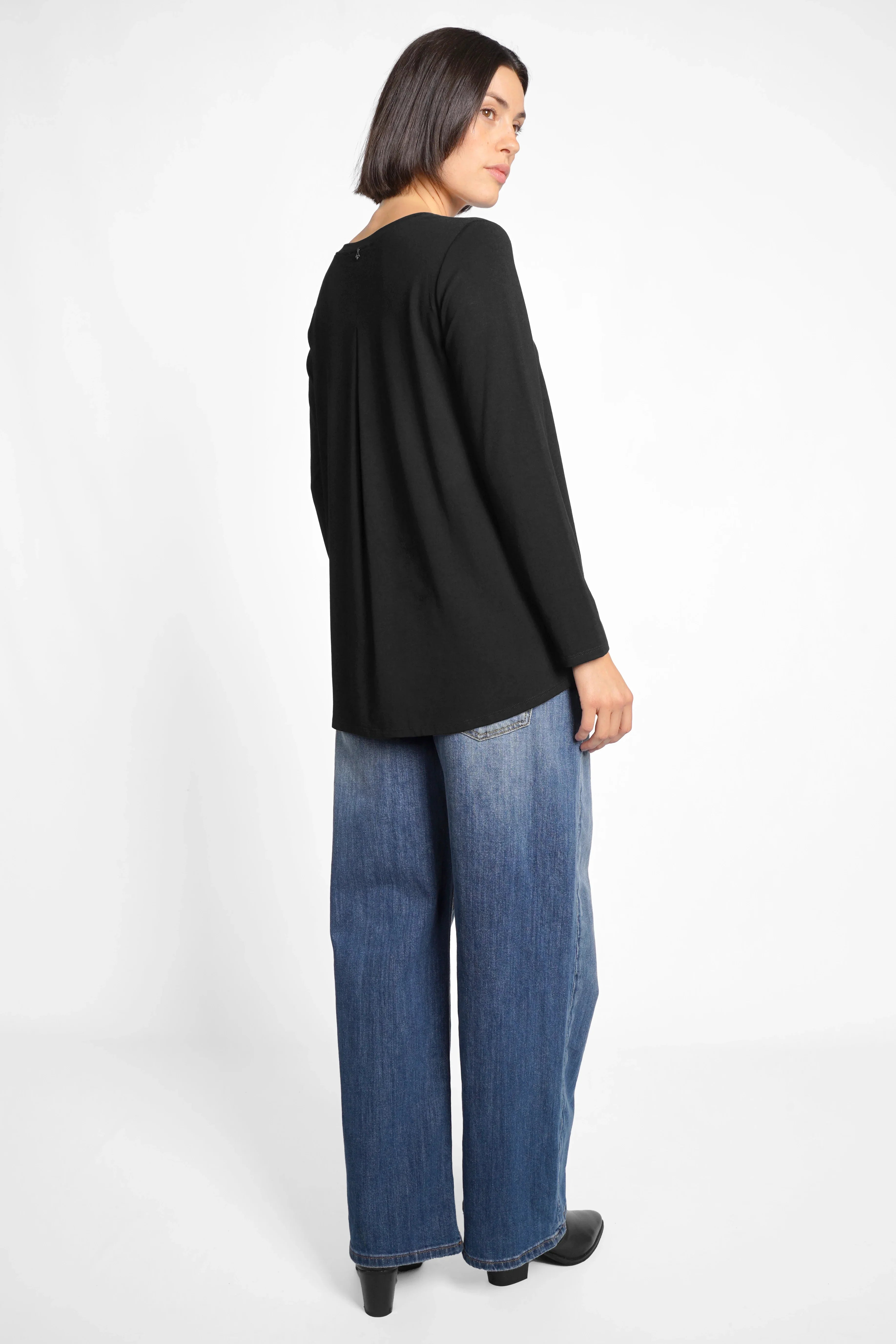 Woman wearing black LYLLDA Viskose long sleeve top with back pleat and relaxed fit paired with wide-leg jeans