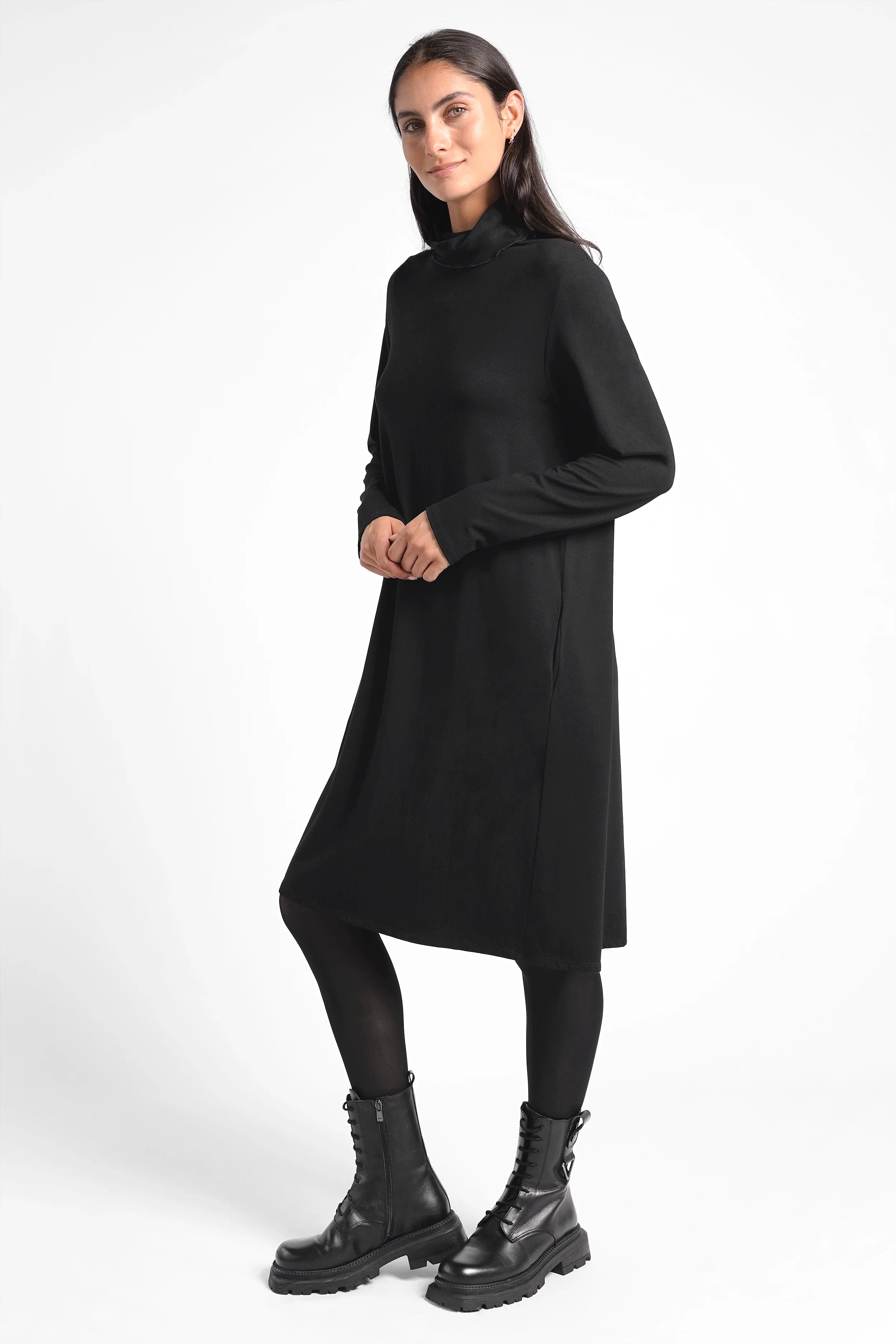 Frau trägt schwarzes LYLLDA Turtleneck Kleid in A-Linie mit Seitentaschen und Rückenfalte