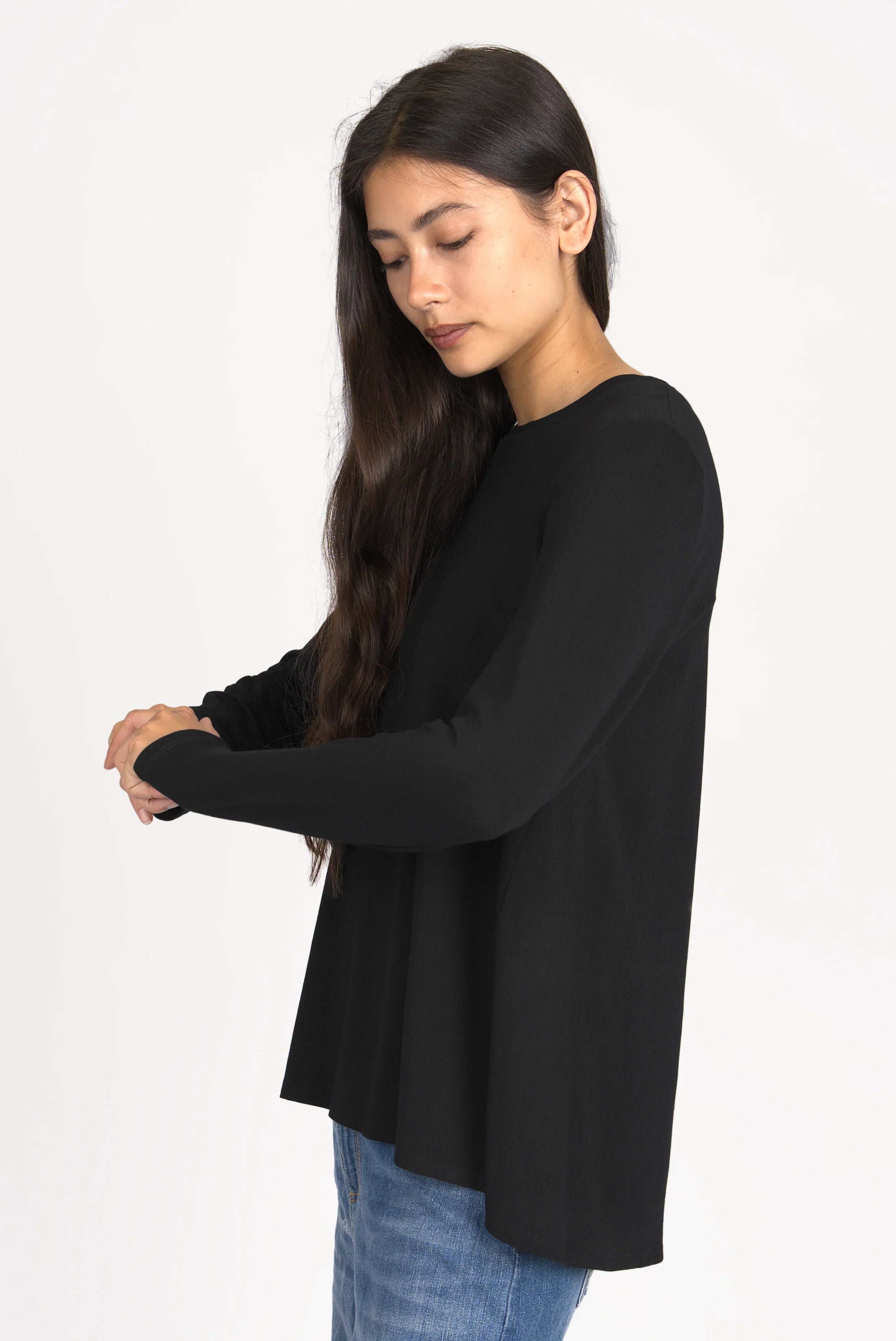 Woman wearing black LYLLDA Viskose Longsleeve with round neckline and relaxed fit, side view.