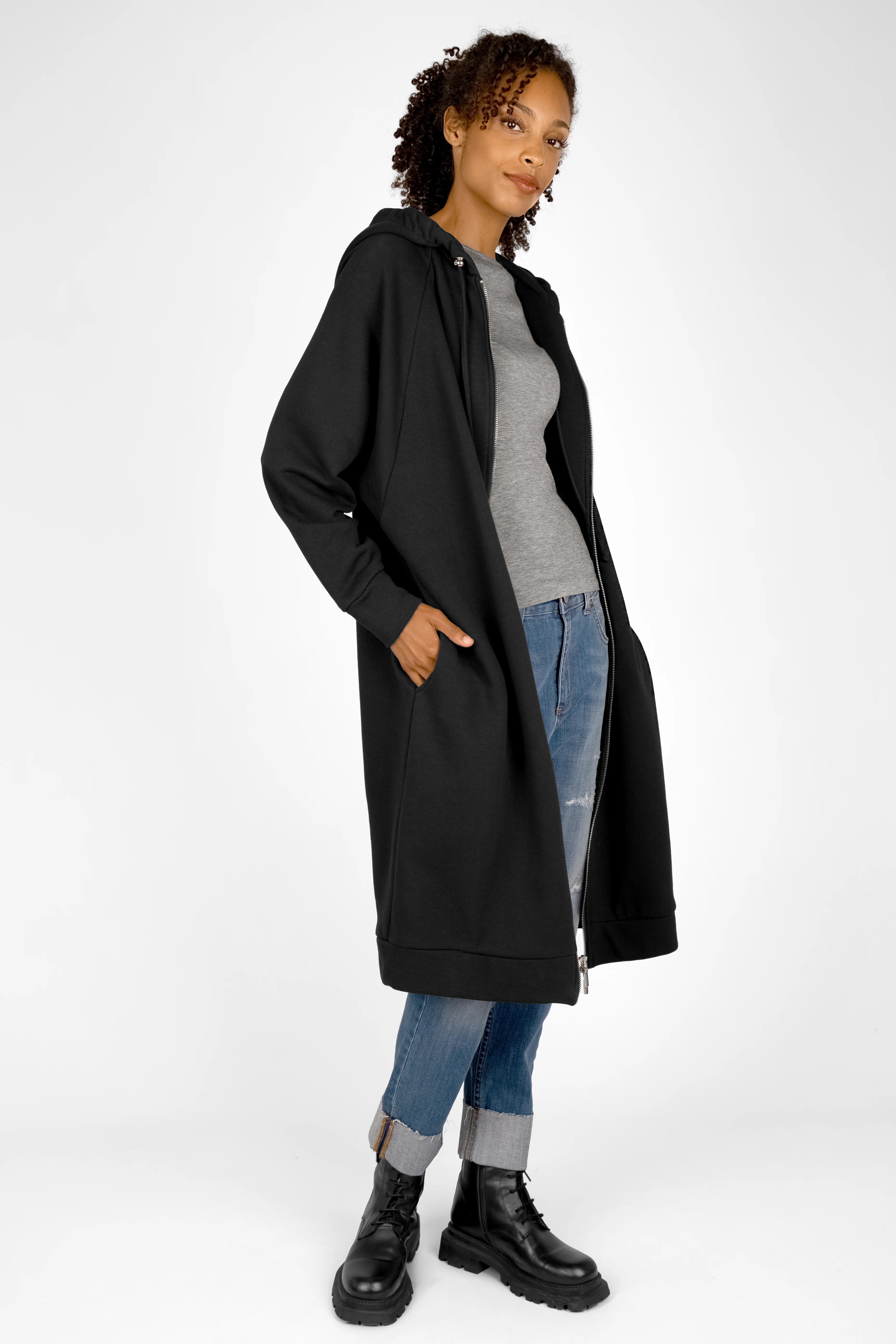 Woman wearing black MANDI.K Longzip-Hoodie with large hood, side pockets, and relaxed fit over casual outfit