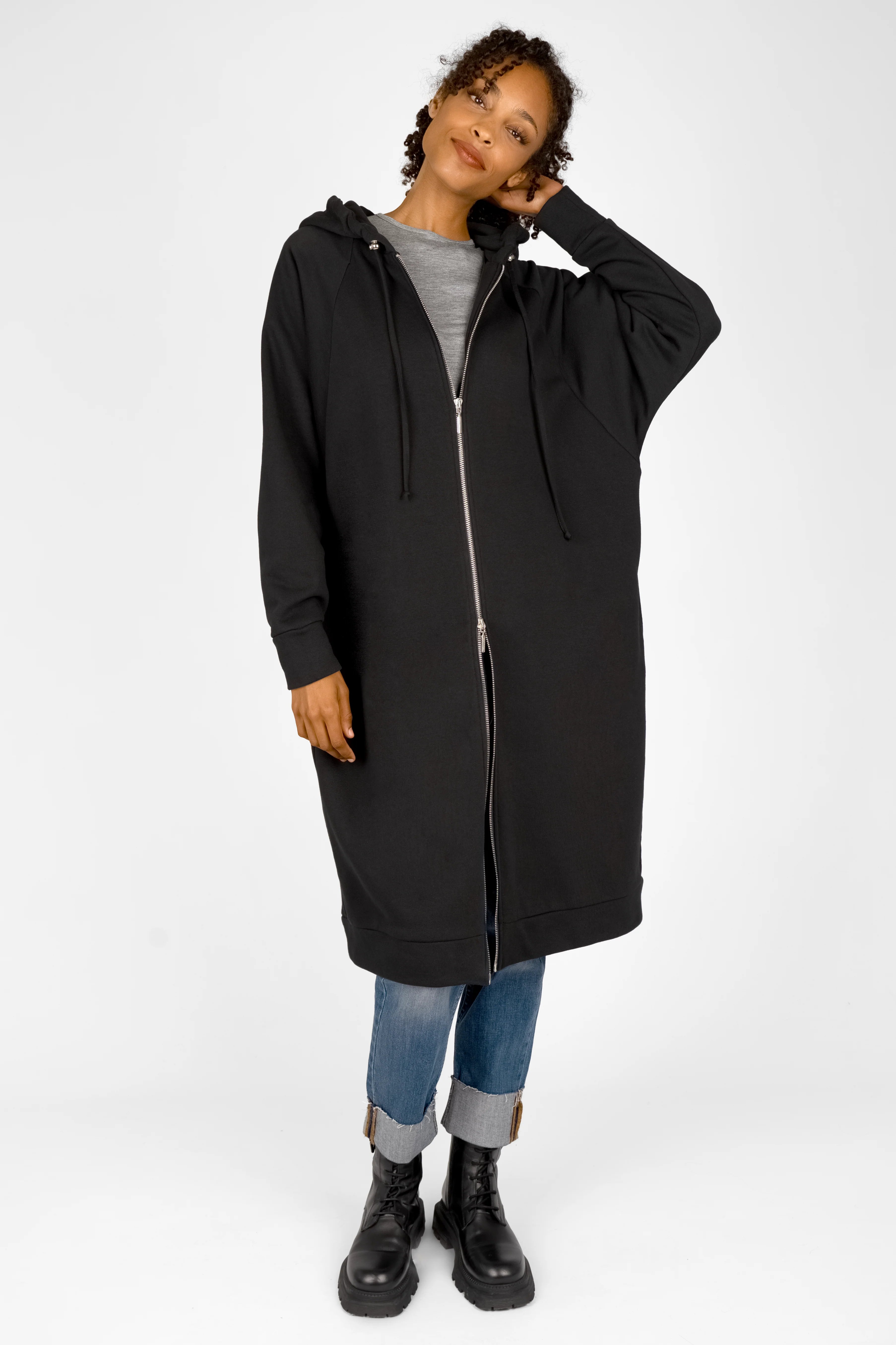 Woman wearing black MANDI.K Longzip-Hoodie with two-way zipper, large hood, and side pockets