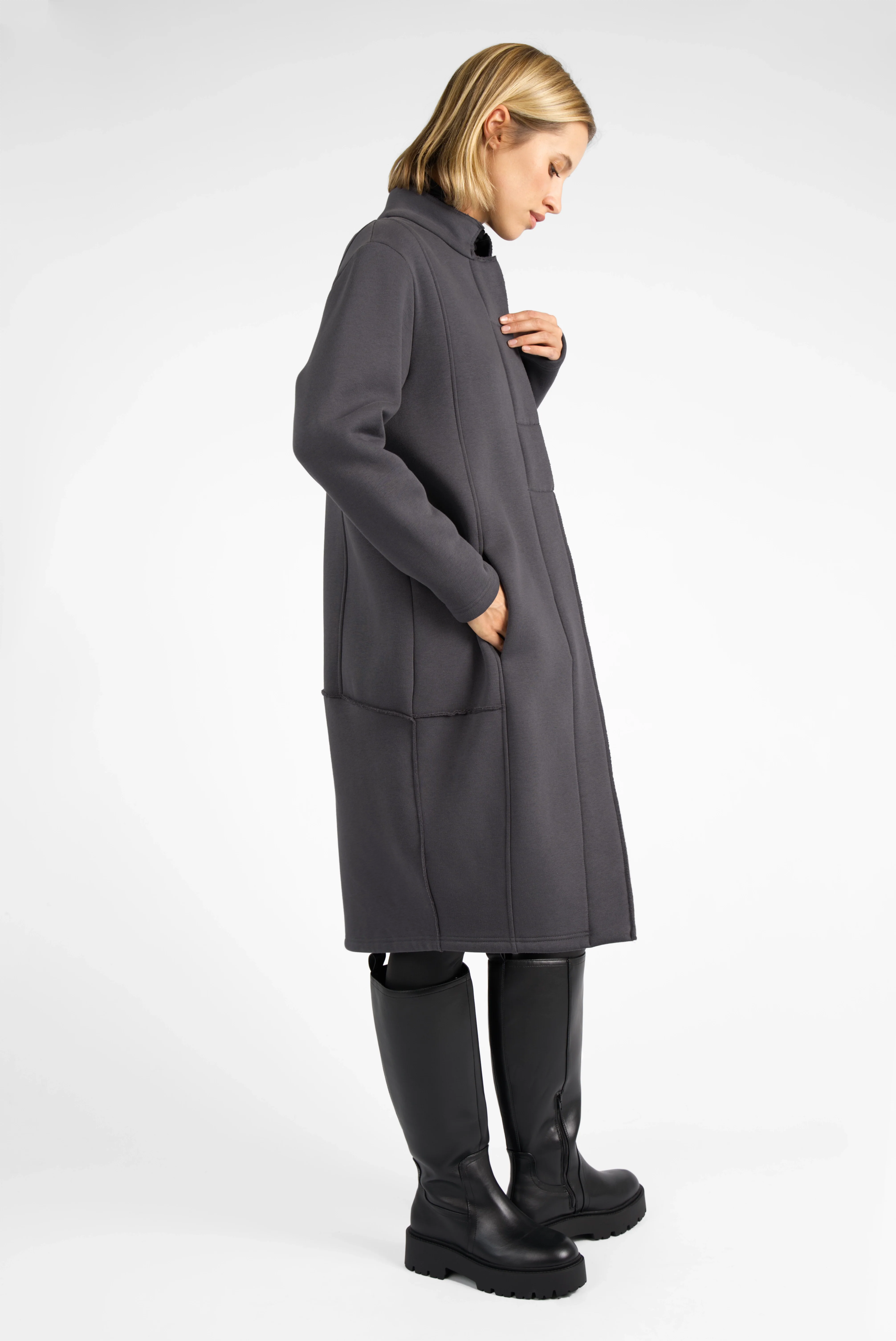 Side view of a model wearing a grey MANEY Sweatmantel with raw-cut seams and concealed button placket