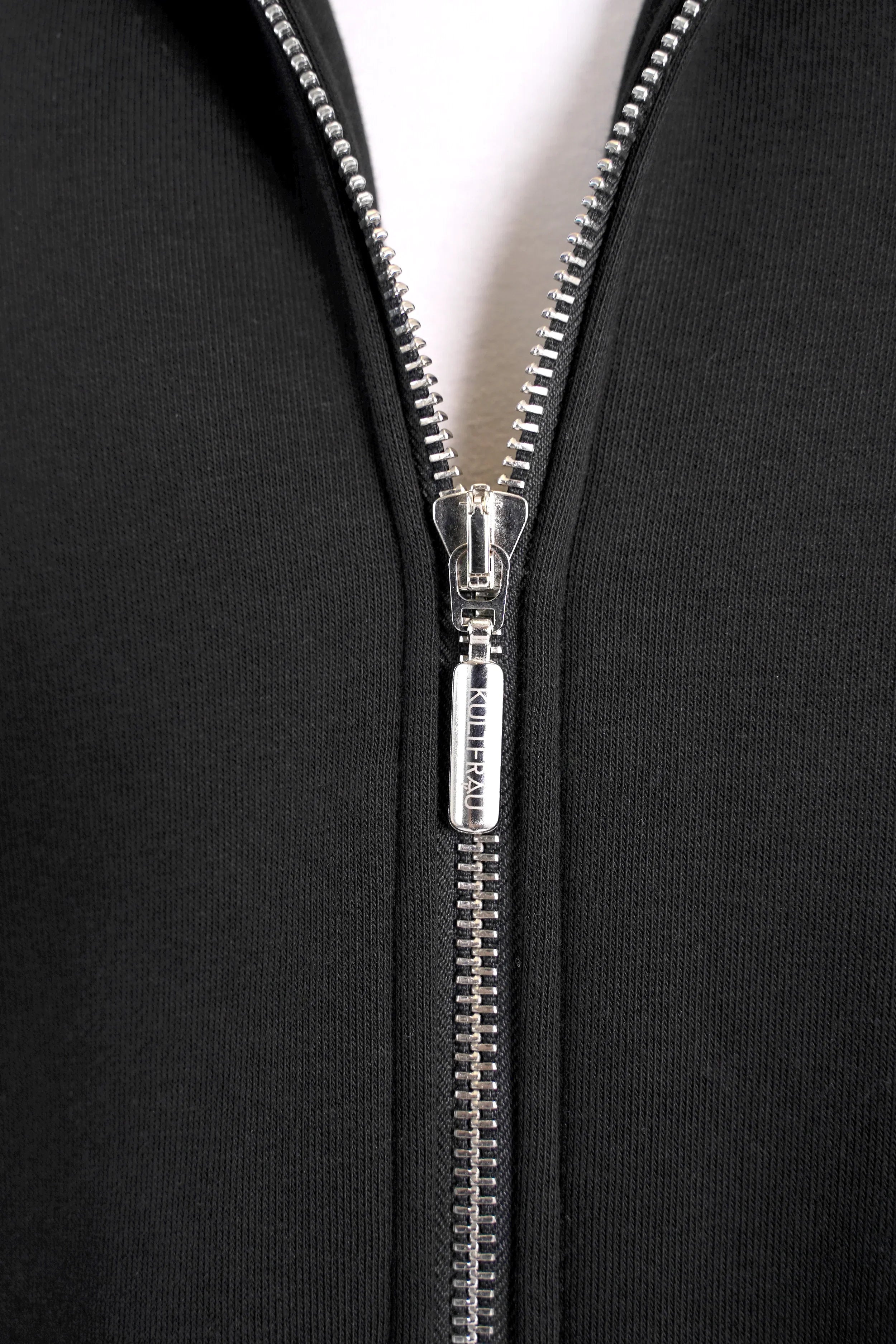 Close-up of black Longzip-Hoodie zipper detail with silver two-way zip and fabric texture.