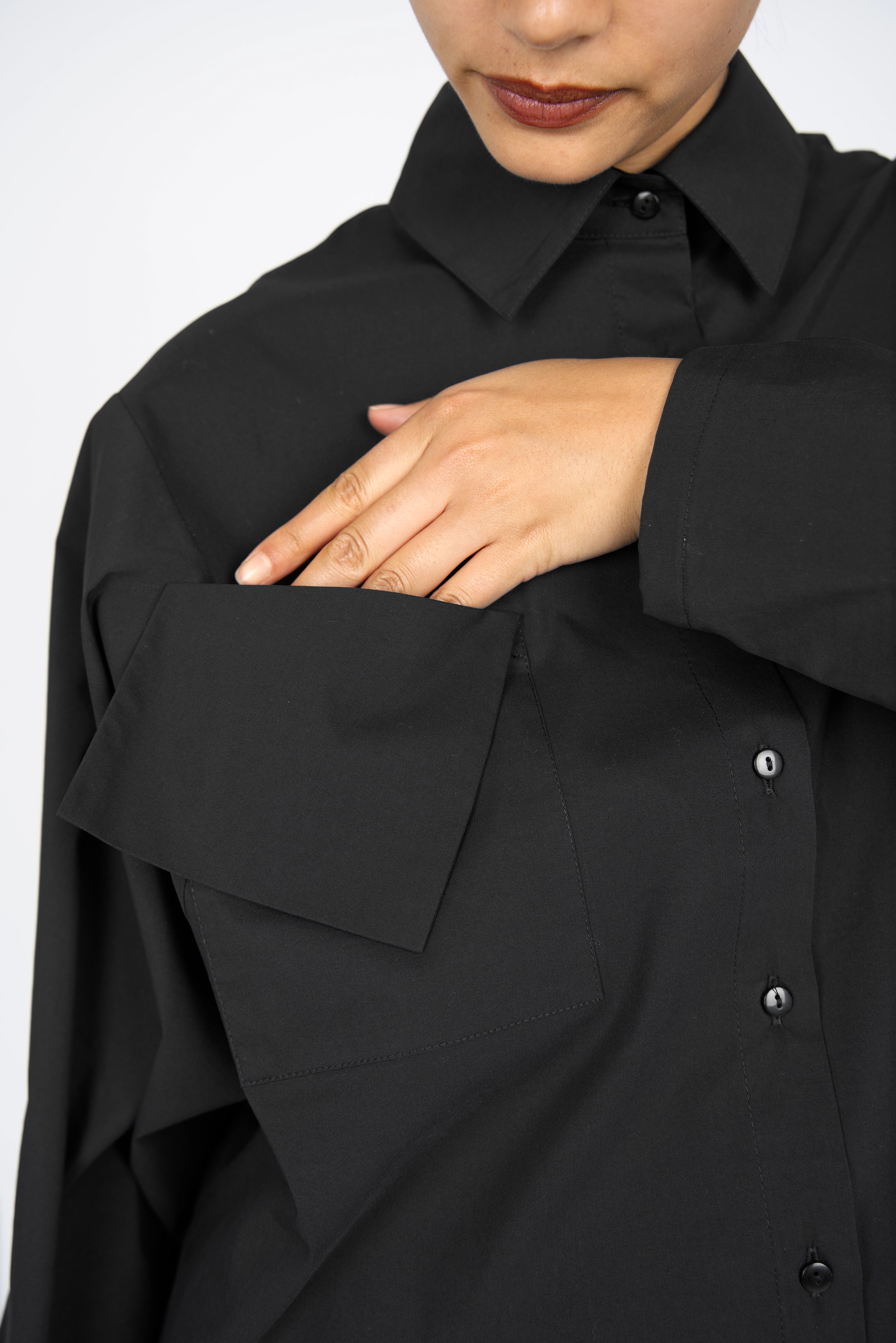 Black MELIZA Bluse with relaxed fit, bat-cut sleeves, asymmetrical flap pockets, and smooth popeline fabric with stretch.