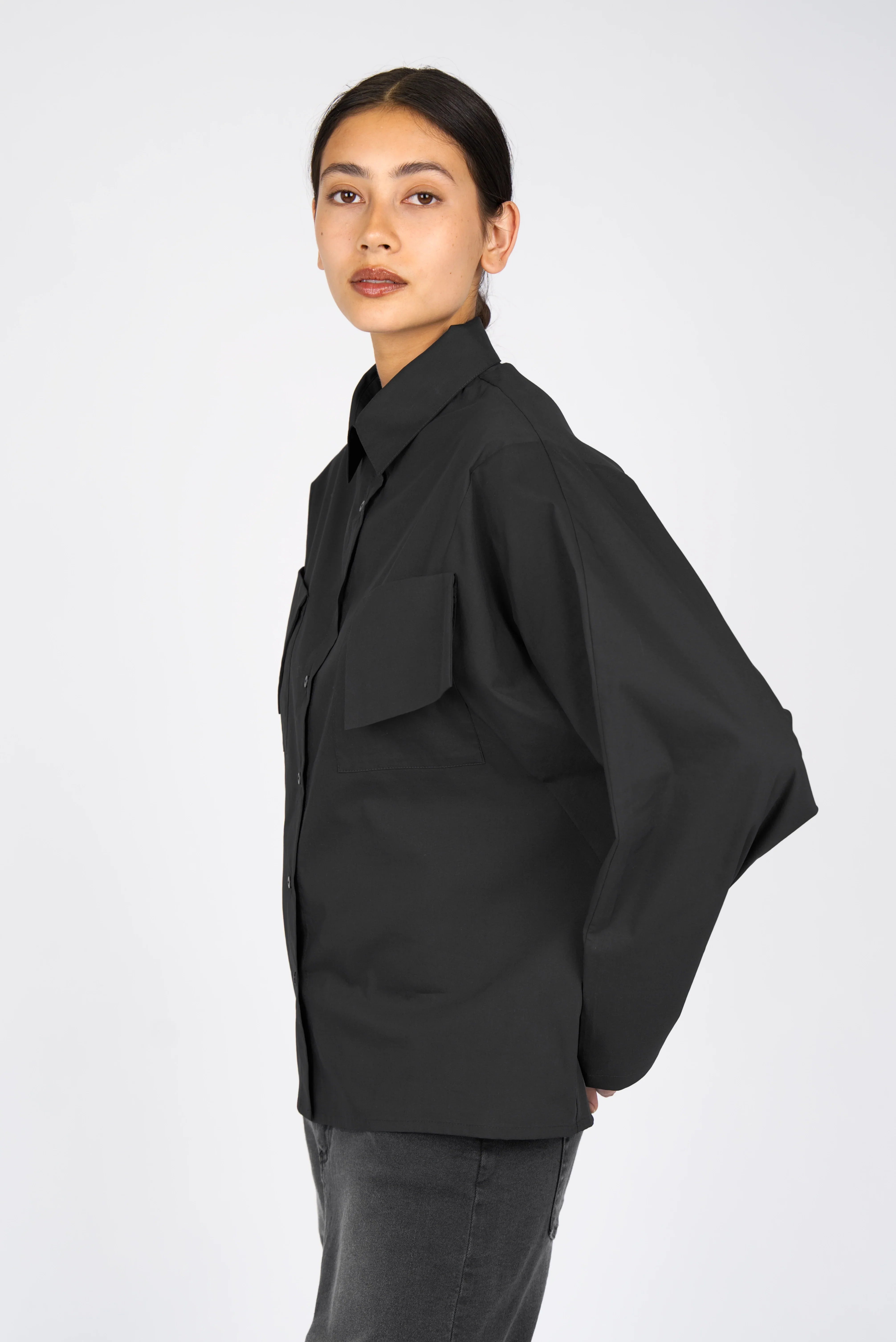 Woman wearing black MELIZA Bluse blouse with bat-cut sleeves and asymmetrical patch pockets in relaxed fit.