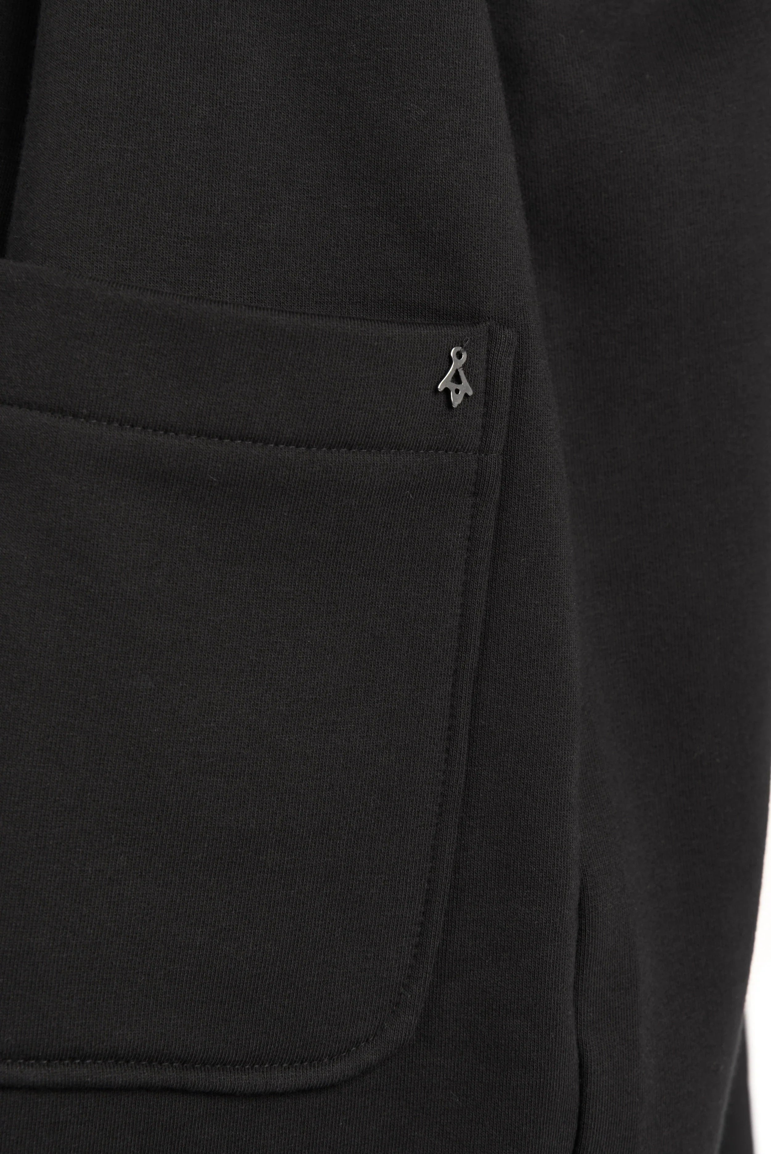 Detailaufnahme der großen aufgesetzten Tasche des schwarzen MONDY.K Oversize Sweatmantels aus weichem Jersey