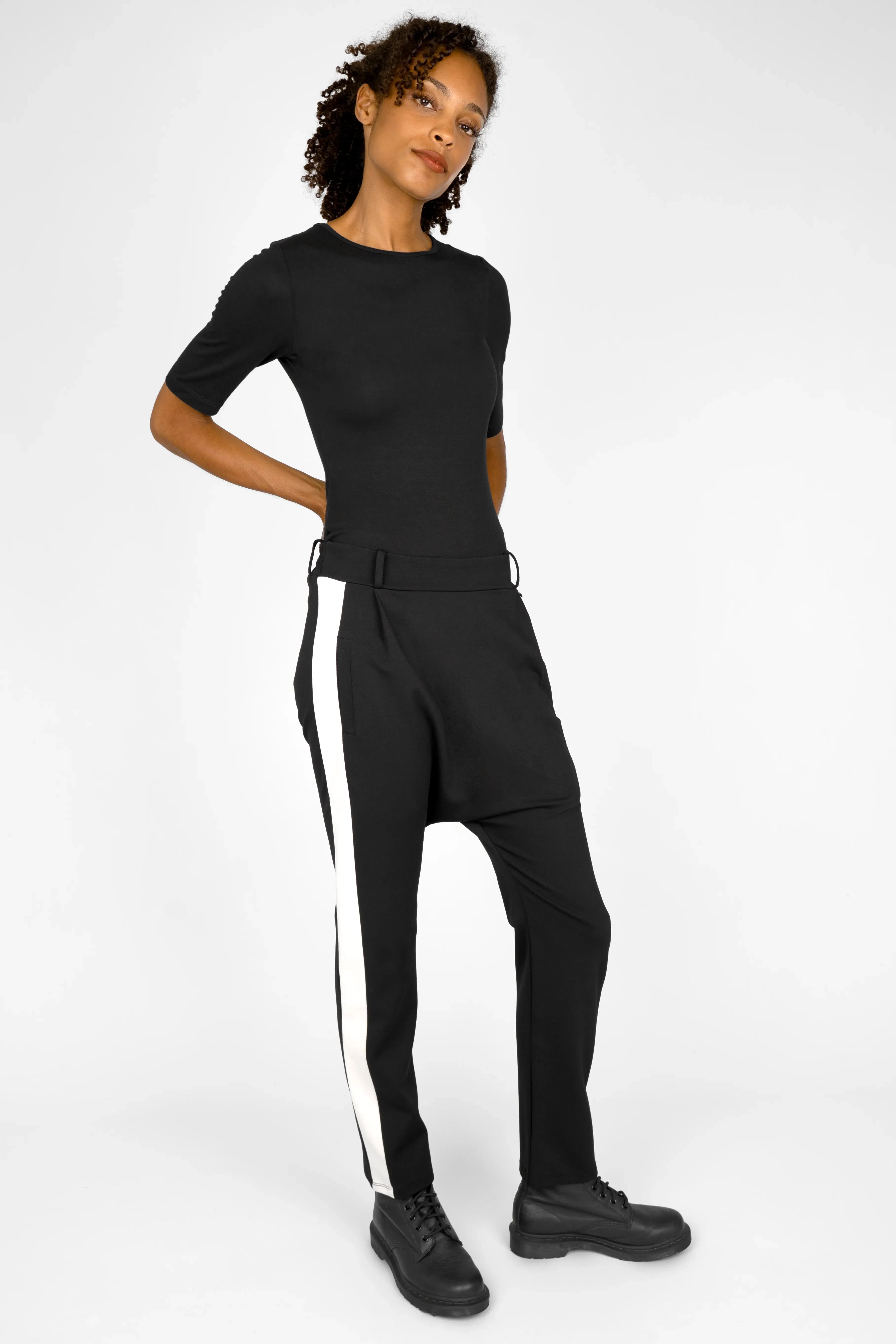 Woman wearing MYRAN Tapered Sweathose black sweatpants with white side stripes and optional belt