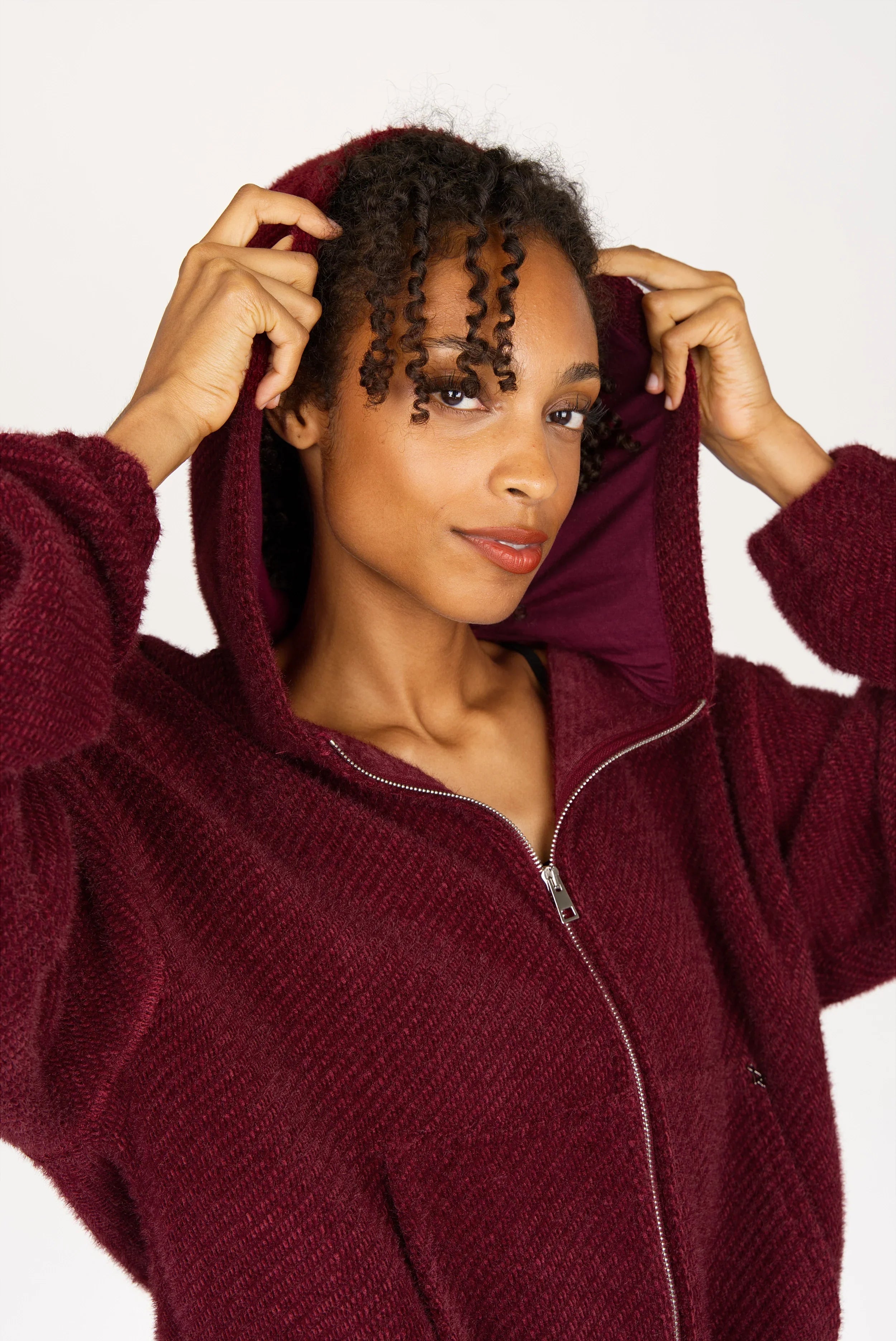 Frau trägt bordeauxroten Zip-Hoodie mit samtig weicher Effektgarn-Struktur und Kapuze
