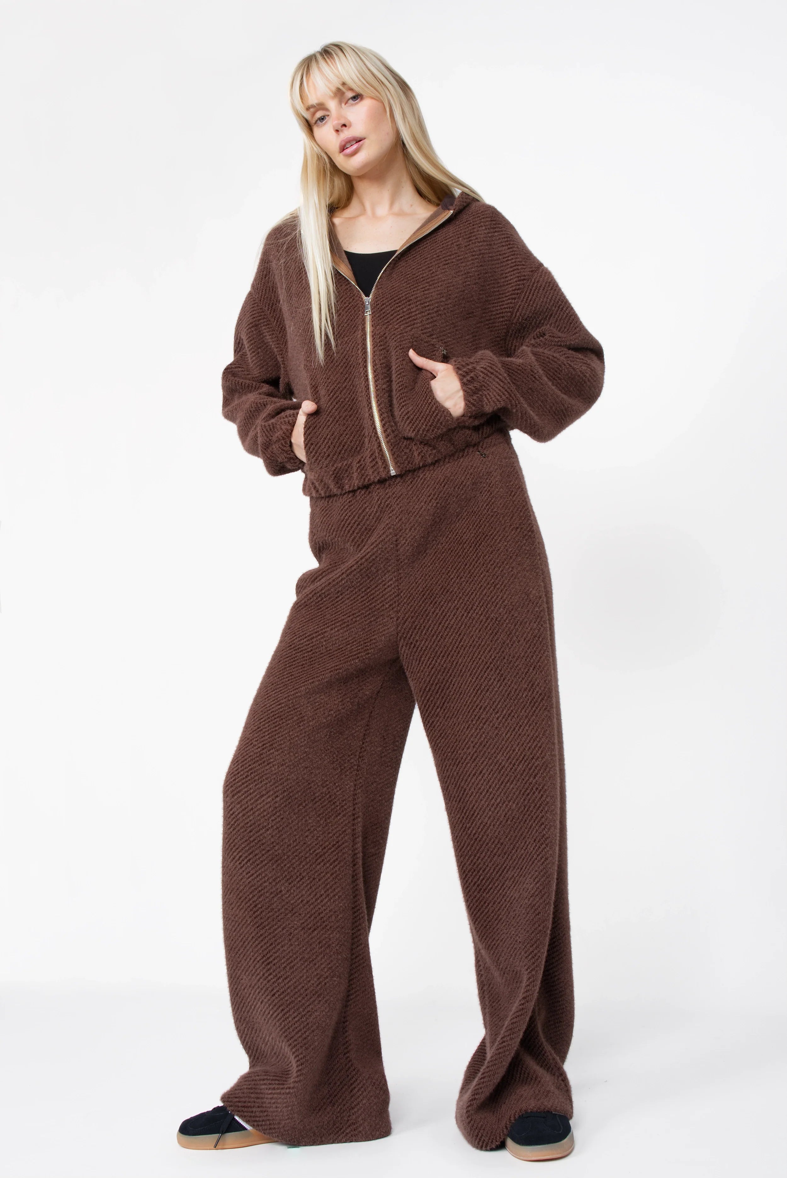 Frau trägt braunen NAEMAI Zip-Hoodie mit samtig weicher Kurzhaarfell-Struktur und passenden weiten Hosen
