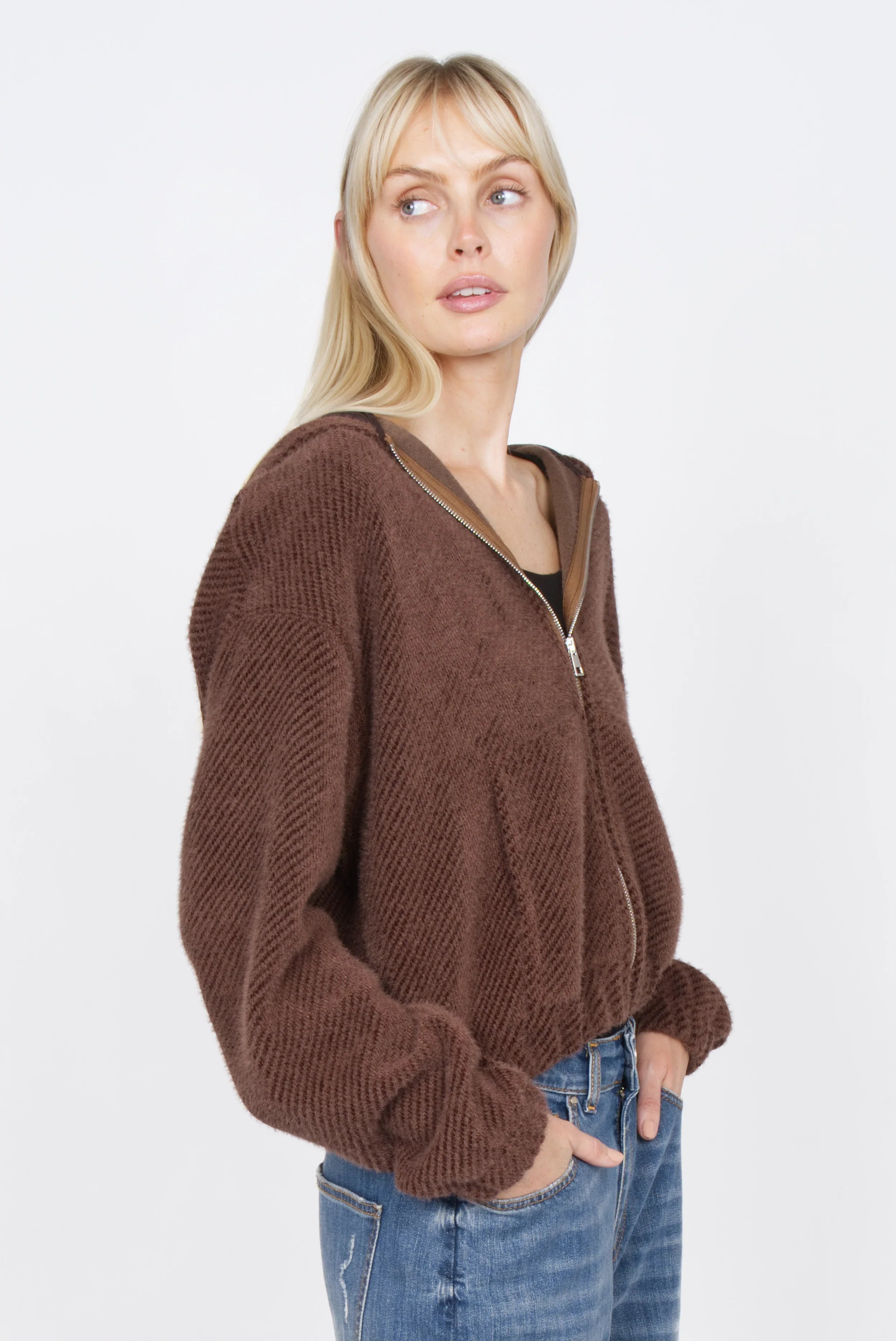 Frau trägt braunen Zip-Hoodie mit samtig weicher Kurzhaarfell-Struktur und verkürzter Länge