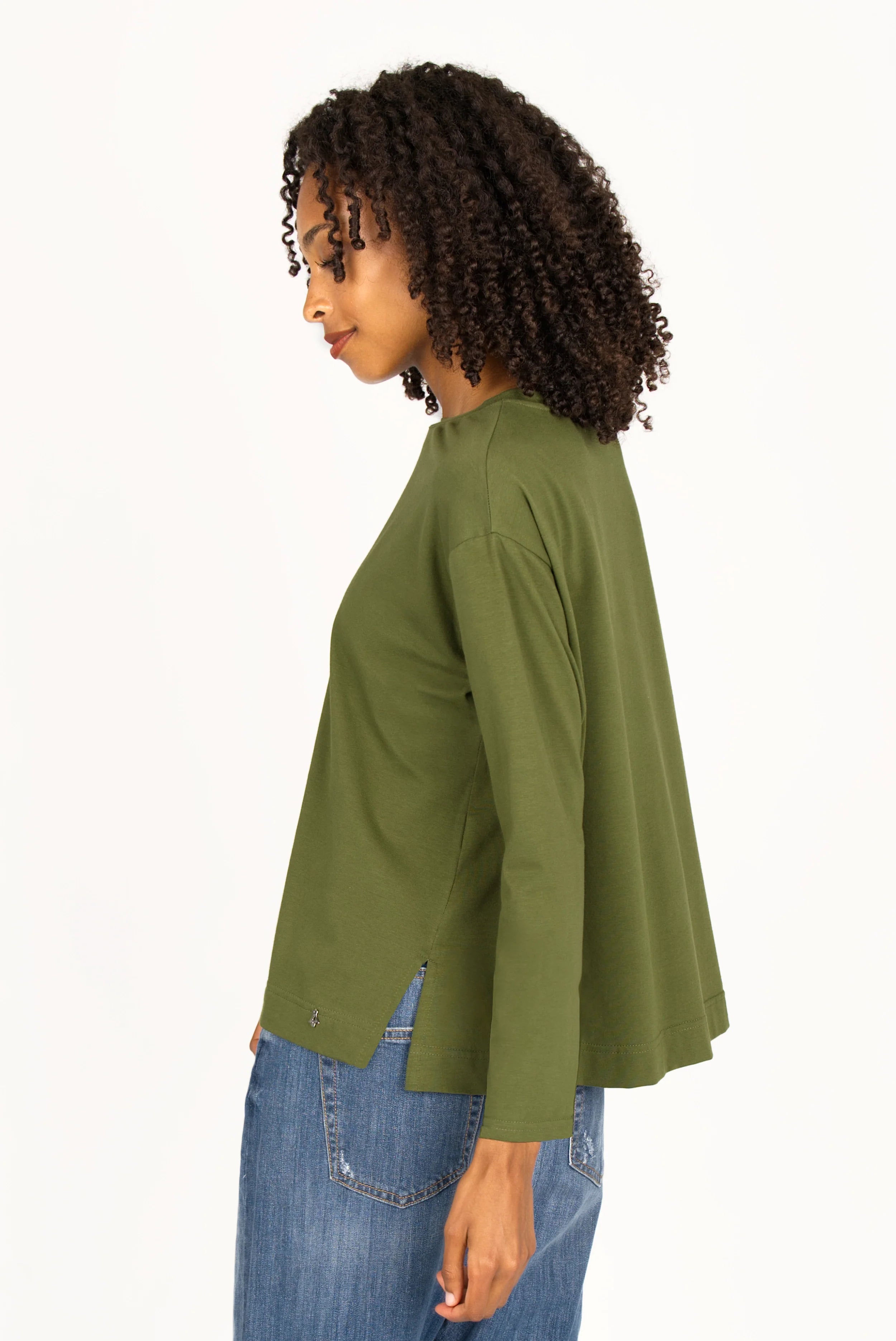 Woman wearing olive green NITI.K Langarm Shirt with long sleeves and side slits paired with blue jeans