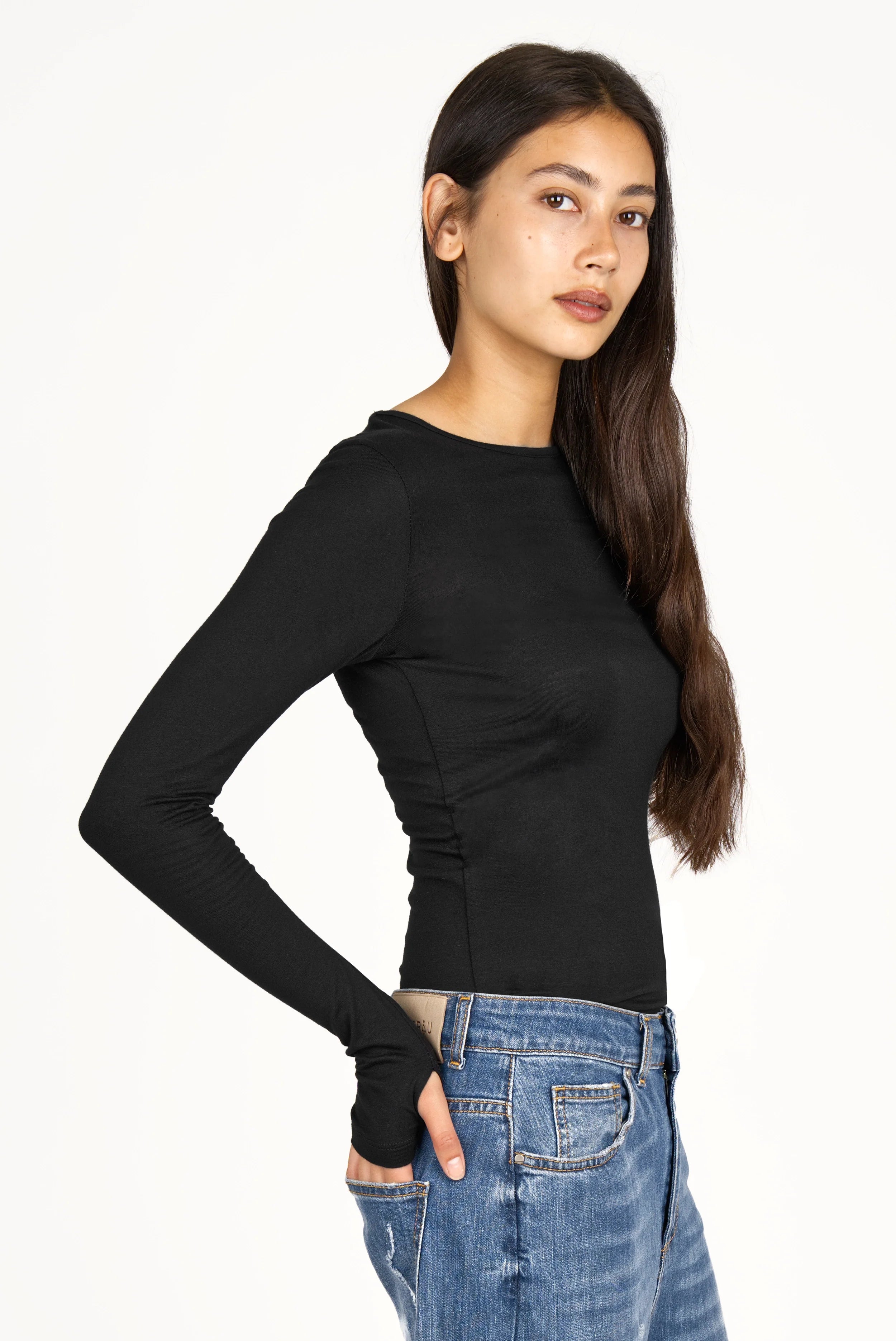 Woman wearing black NJELI Longsleeve slim fit top with extra long sleeves and thumb holes paired with blue jeans