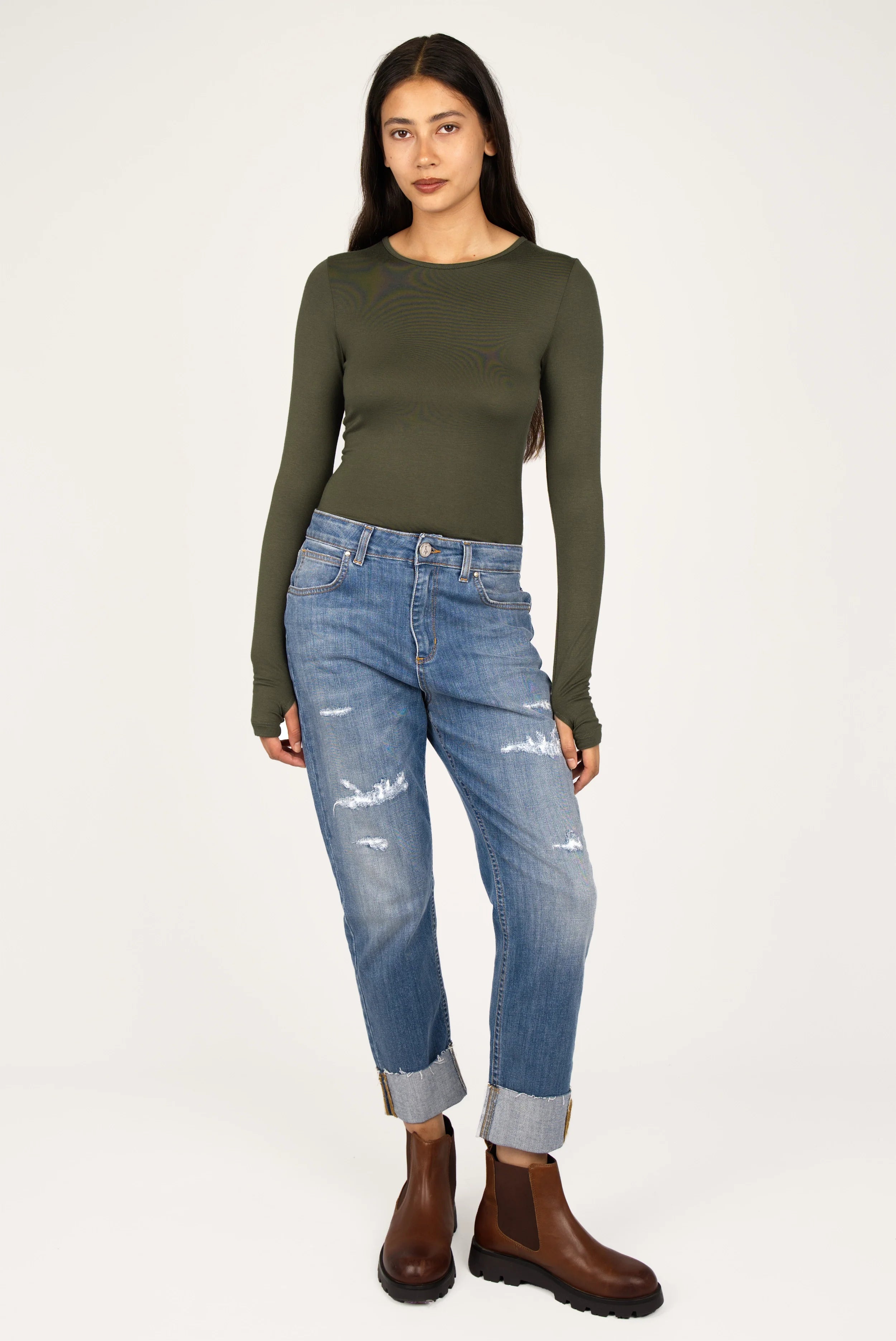 Damen trägt olivegrünes NJELI Longsleeve mit Daumenlöchern und Slim Fit zu blauen Jeans und braunen Stiefeln