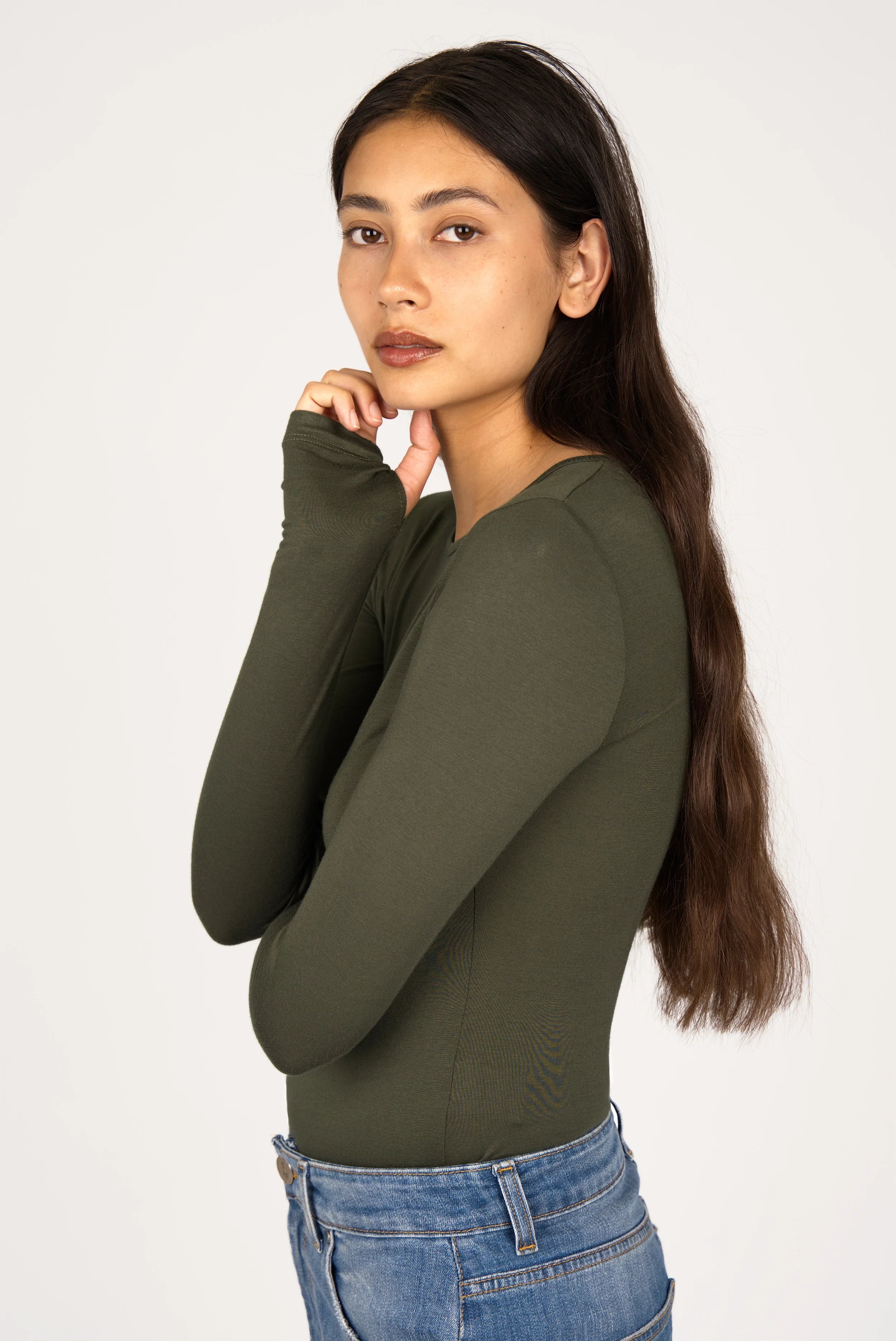 Woman wearing olive green NJELI Longsleeve with thumbholes and slim fit paired with blue jeans