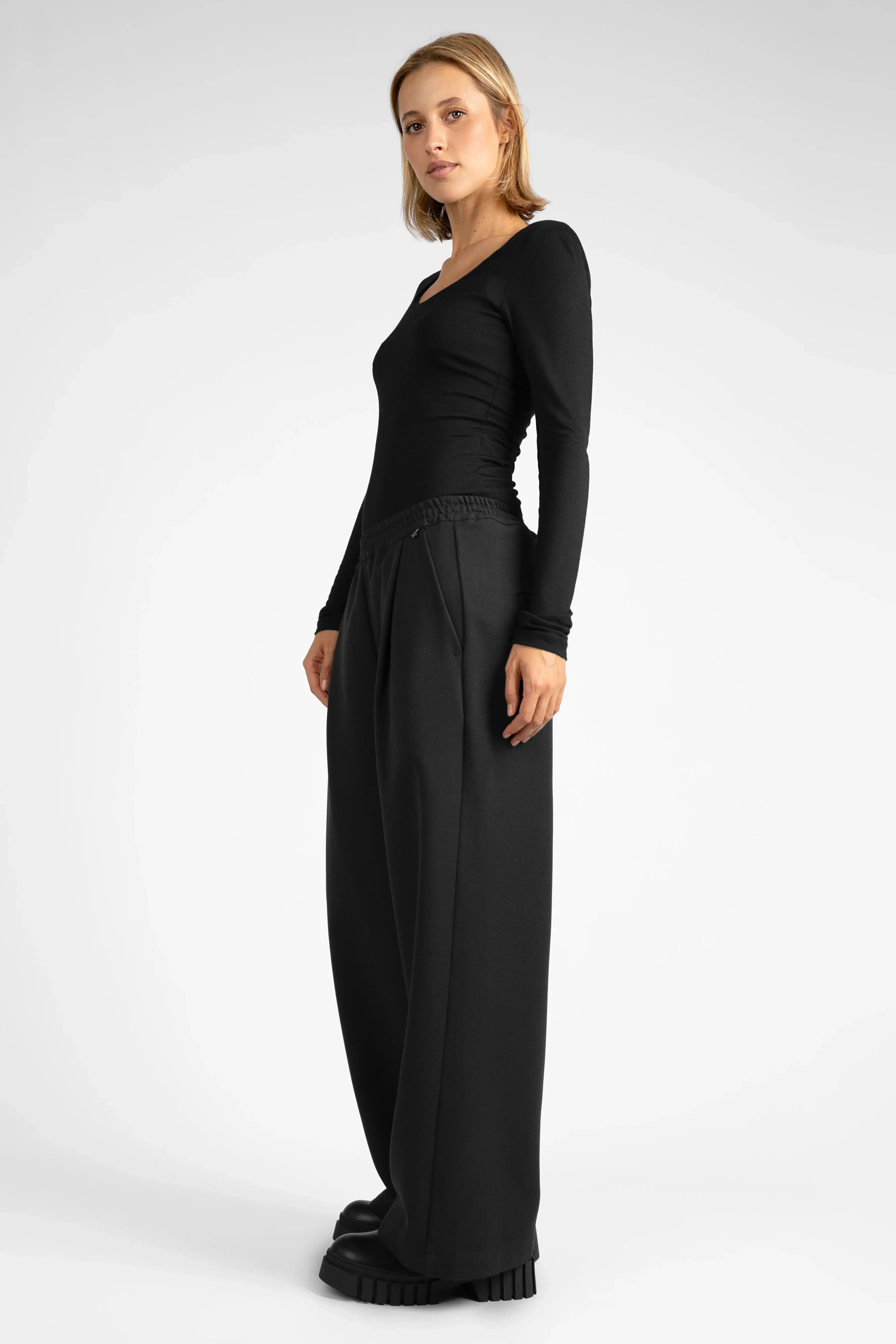 Frau trägt schwarze ONA Wide-Leg Hose mit elastischem Bund und seitlichen Taschen in entspanntem Stil