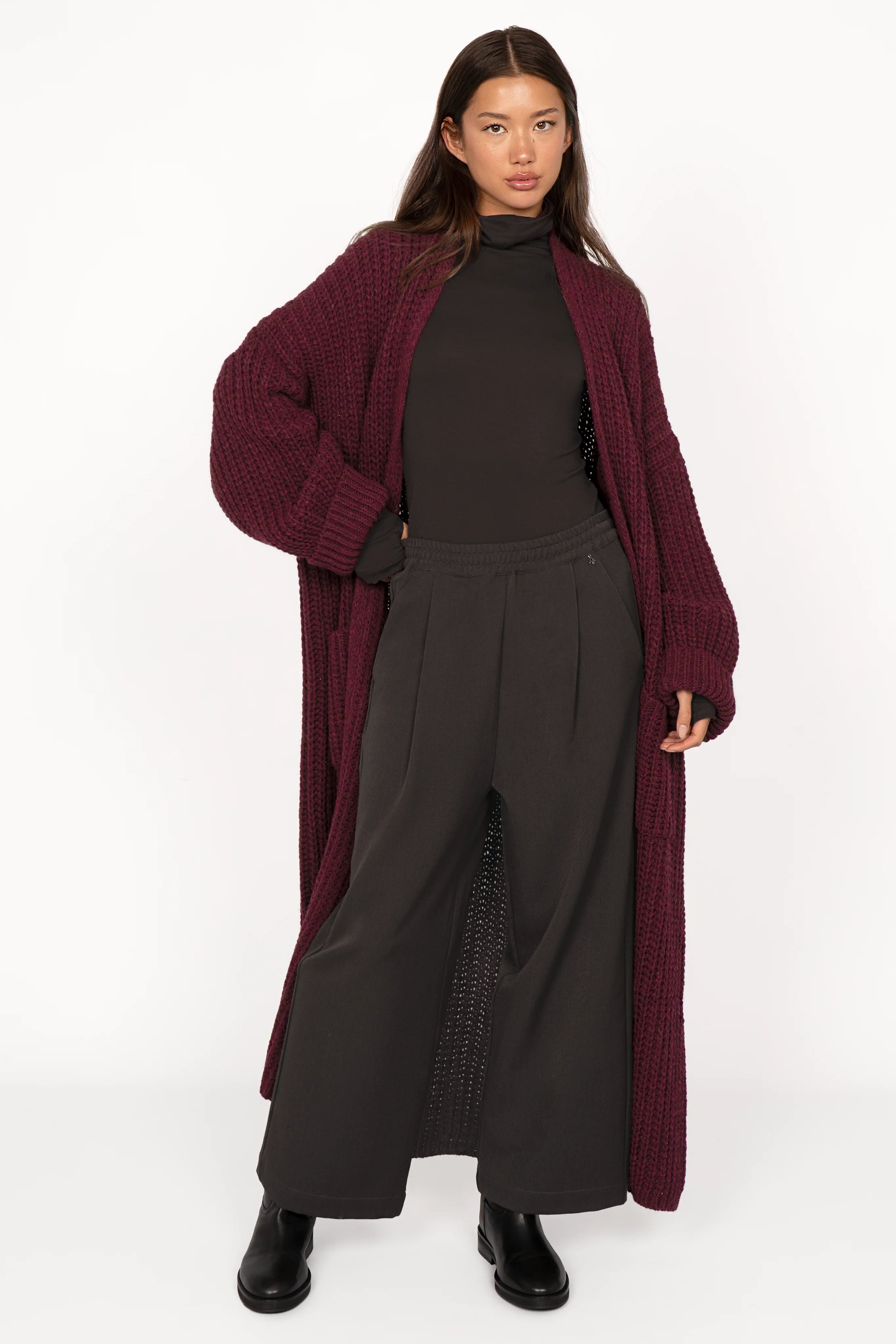 Female model wearing ONAH wide-leg hose with elastic waistband and relaxed fit, paired with maroon long cardigan and black turtleneck.