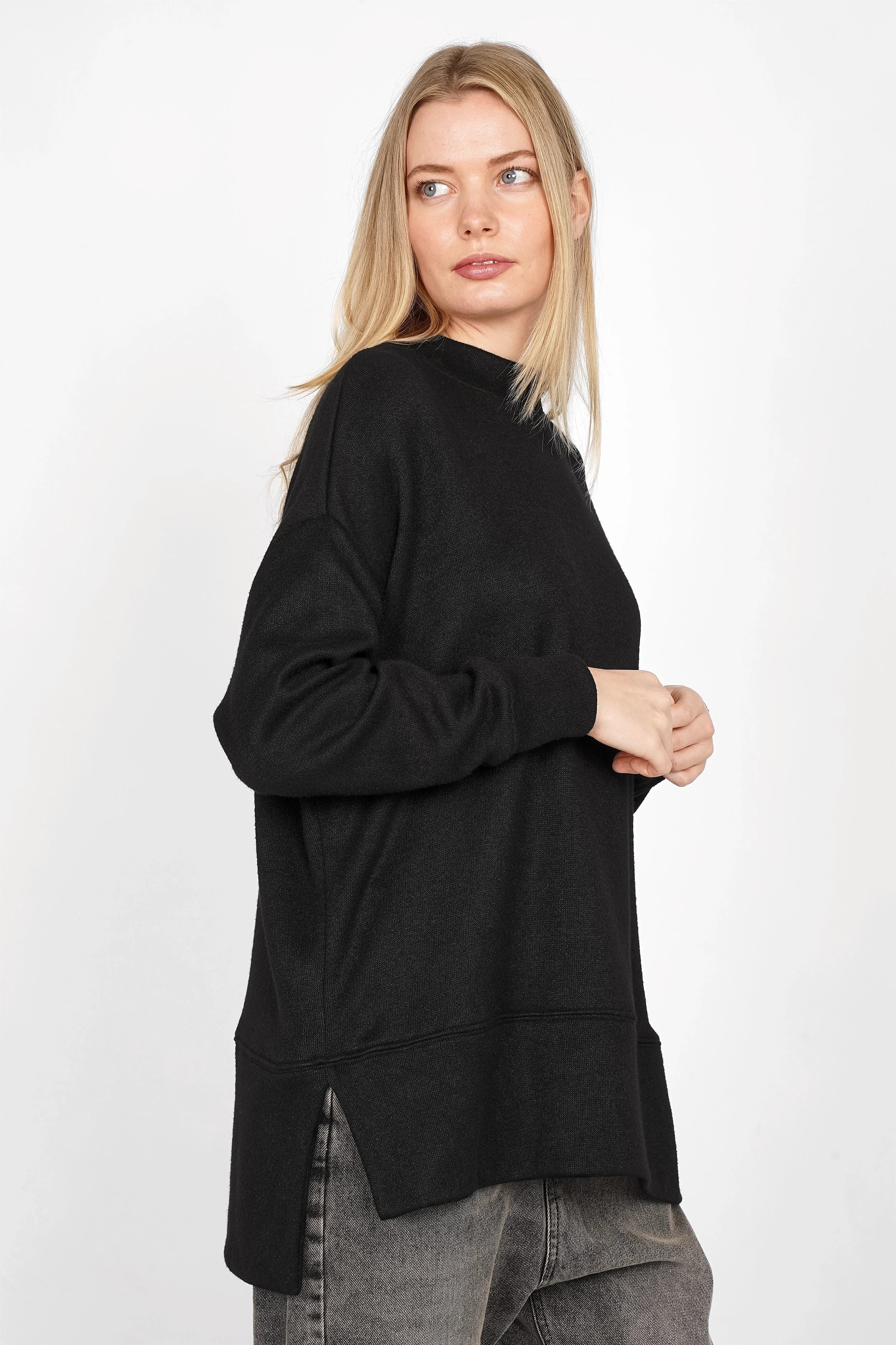 Damen trägt schwarzes PATI.K Oberteil aus softem Feinstrick mit Relaxed Fit, Rundhalsausschnitt und seitlichen Schlitzen