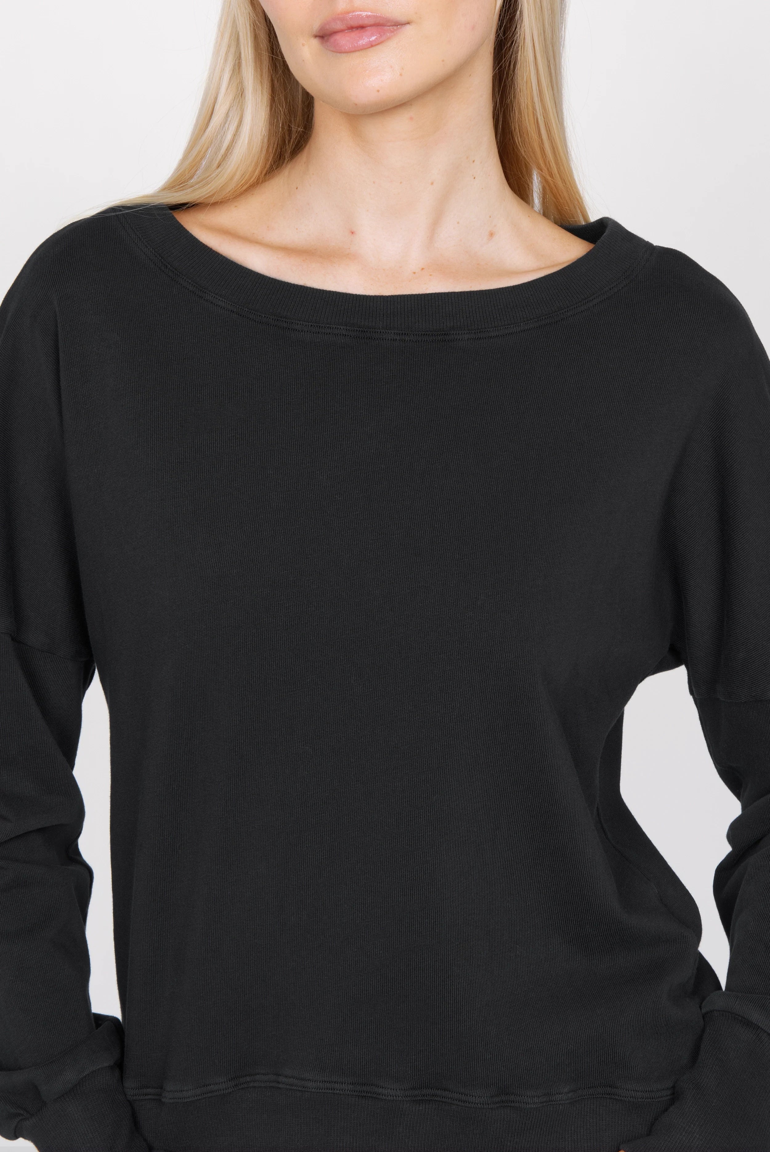 Schwarzes RIISA Longsleeve mit U-Boot Ausschnitt, überschnittenen Schultern und extra breiten Rippbündchen aus Baumwolljersey.