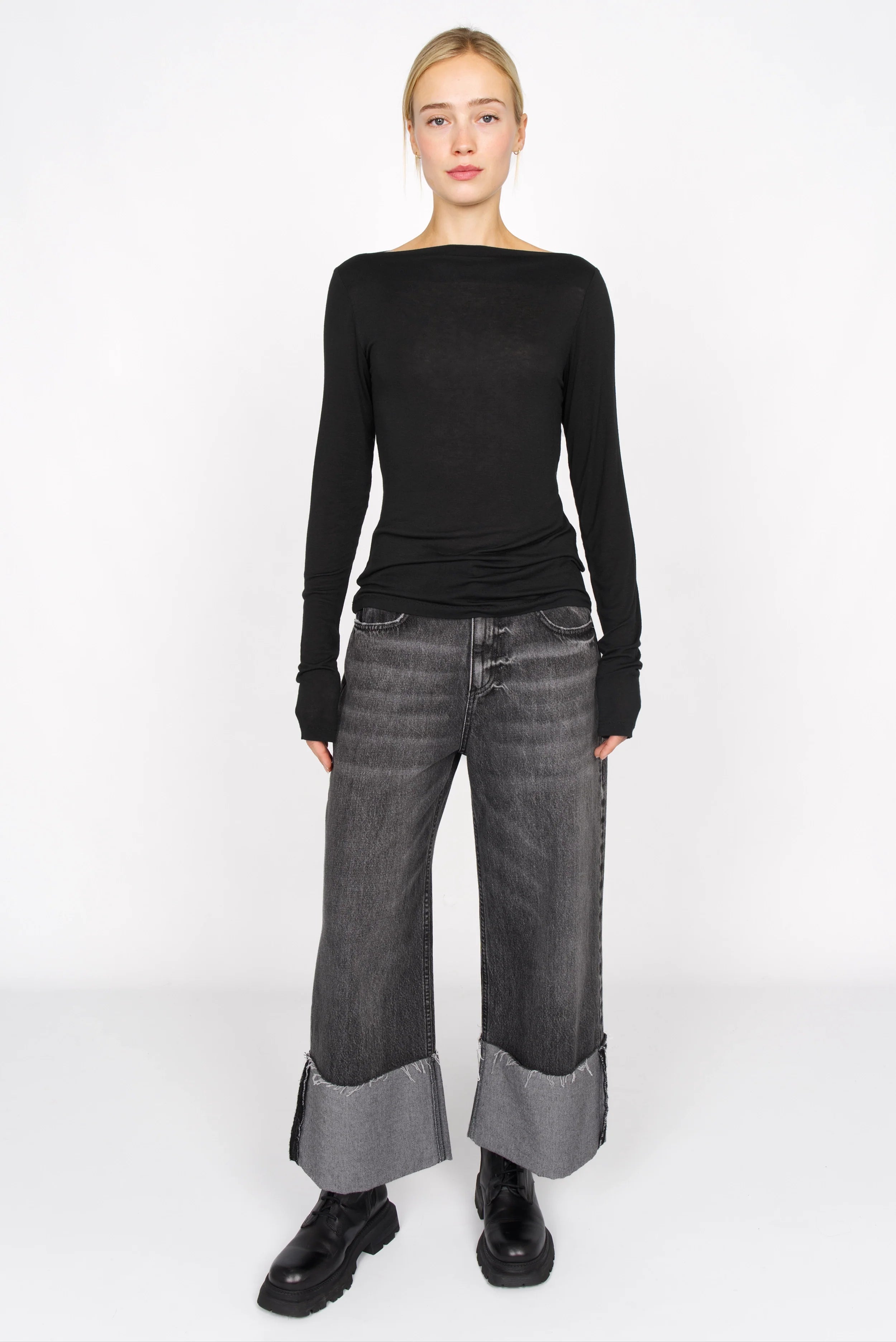 Schwarzes Longsleeve aus Kaschmirmix mit U-Boot Ausschnitt und langen Ärmeln, schmaler Passform, getragen von Model mit schwarzen Jeans und Stiefeln