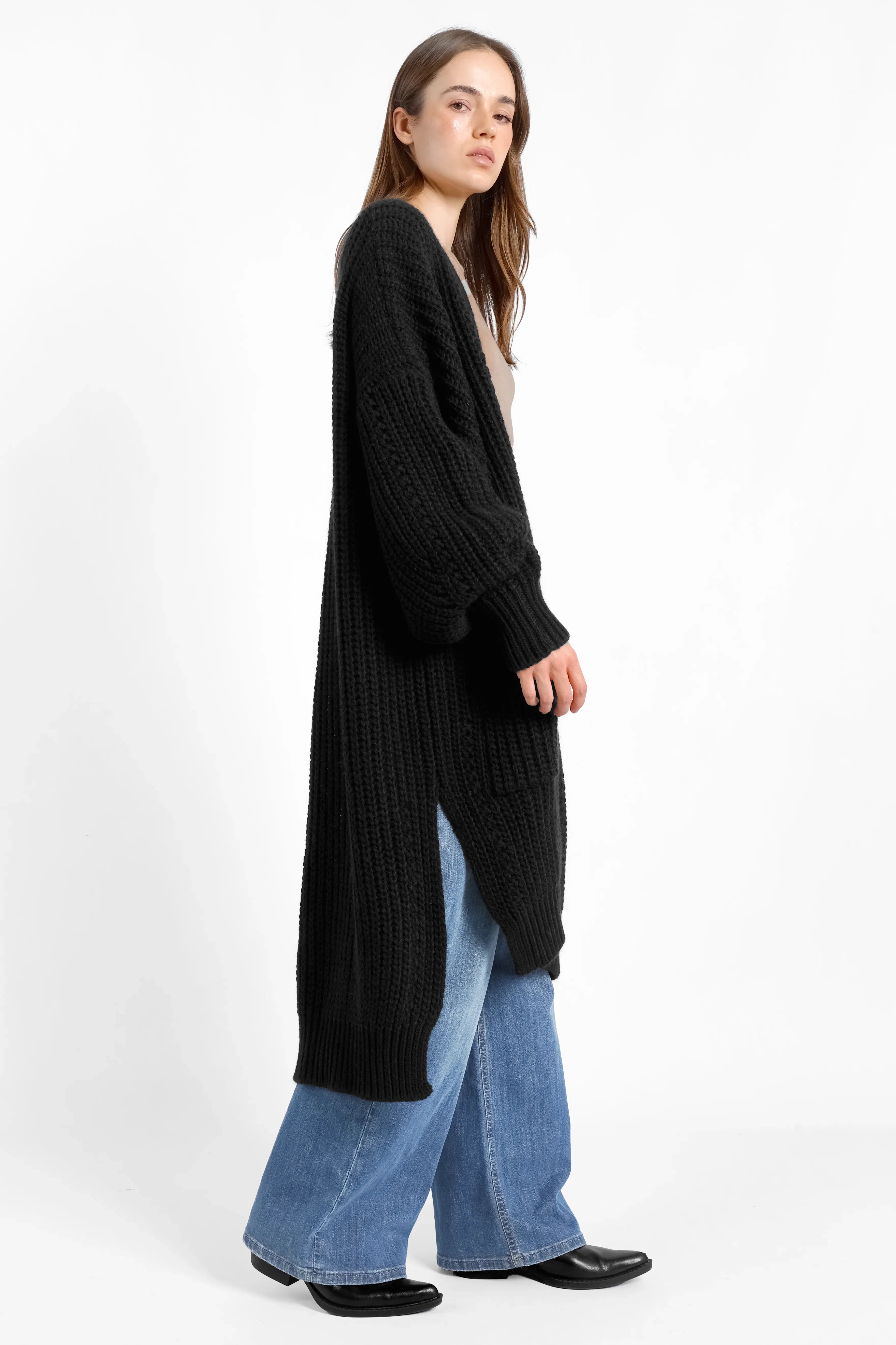 Schwarzer Longcardigan aus Ajour-Strick mit Alpakawolle, Oversize-Schnitt, weiten Ärmeln und seitlichen Schlitzen.