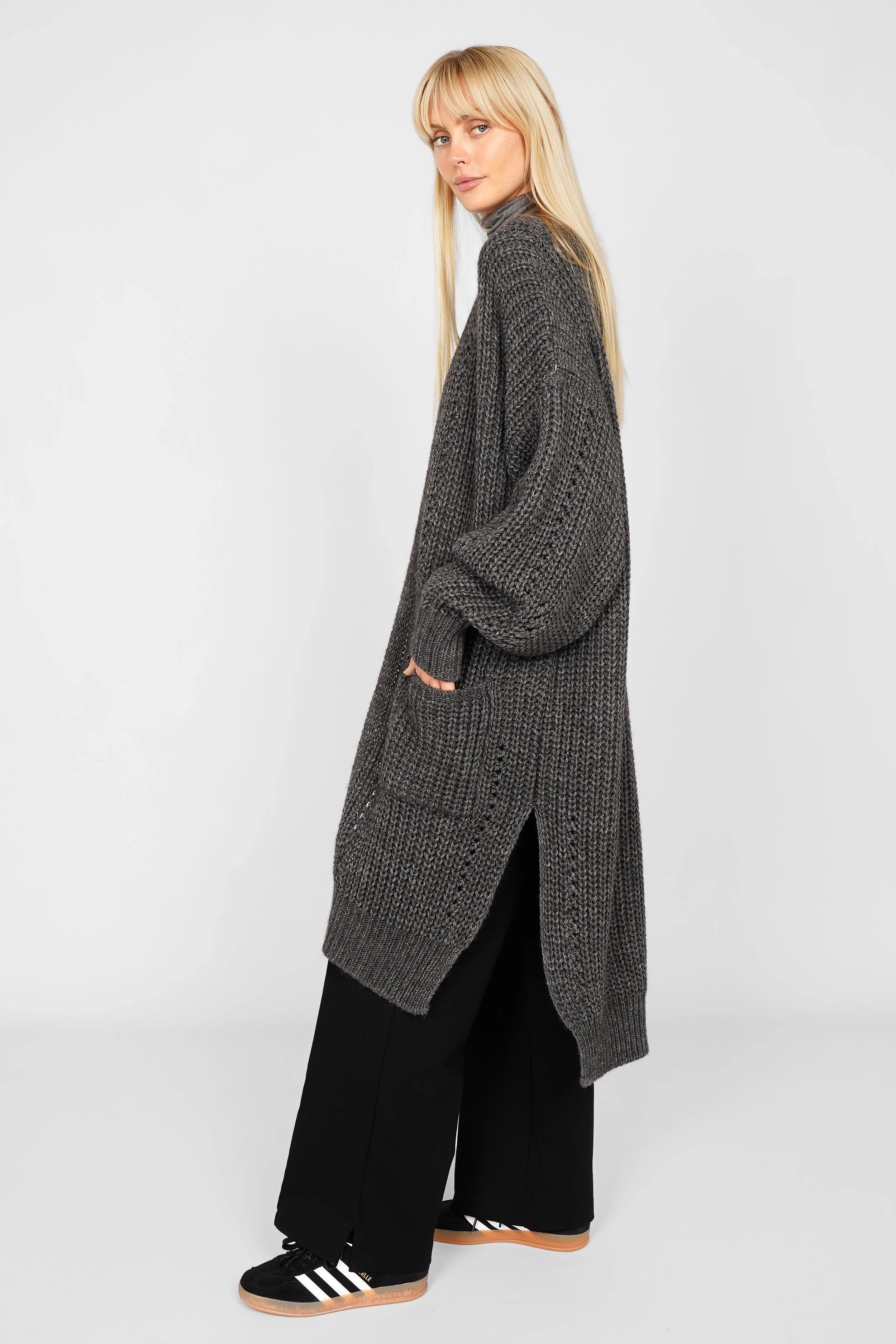 Dunkelgrauer Longcardigan aus Ajour-Strick mit Alpakawolle, oversized mit weiten Ärmeln, aufgesetzten Taschen und seitlichen Schlitzen.