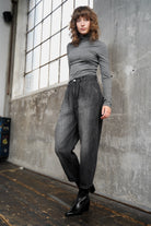 Damen trägt SAIKA Relaxed Tapered Hose aus strukturierter Baumwolle in washed black mit authentischen Whisker-Falten und lockerer Passform