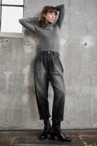 Frau trägt SAIKA Relaxed Tapered Hose in Washed Black mit lockerer Passform und Karottenform vor grauer Wand