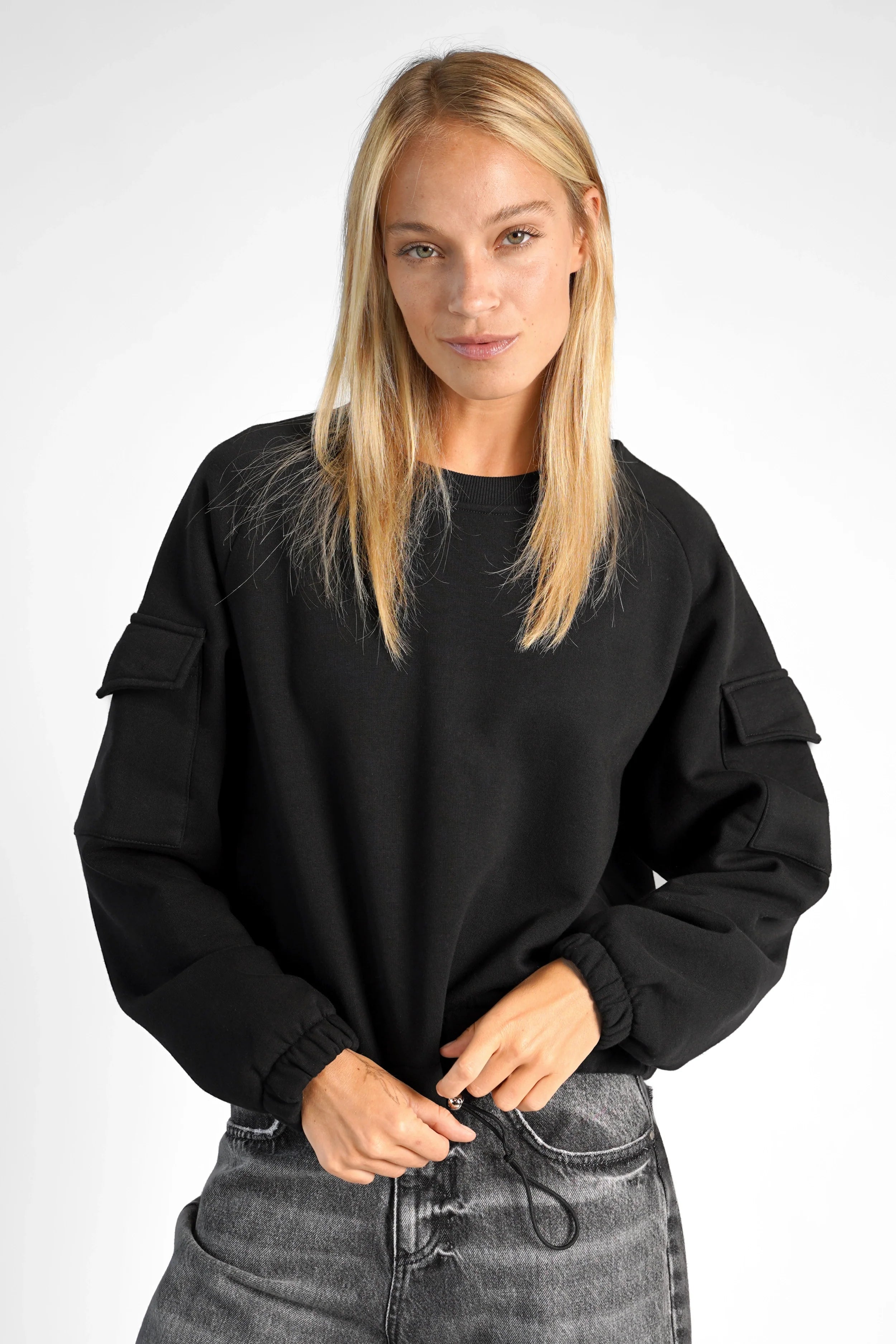 Woman wearing black SEATA Cropped Sweater with oversized fit, round neckline, and front pockets