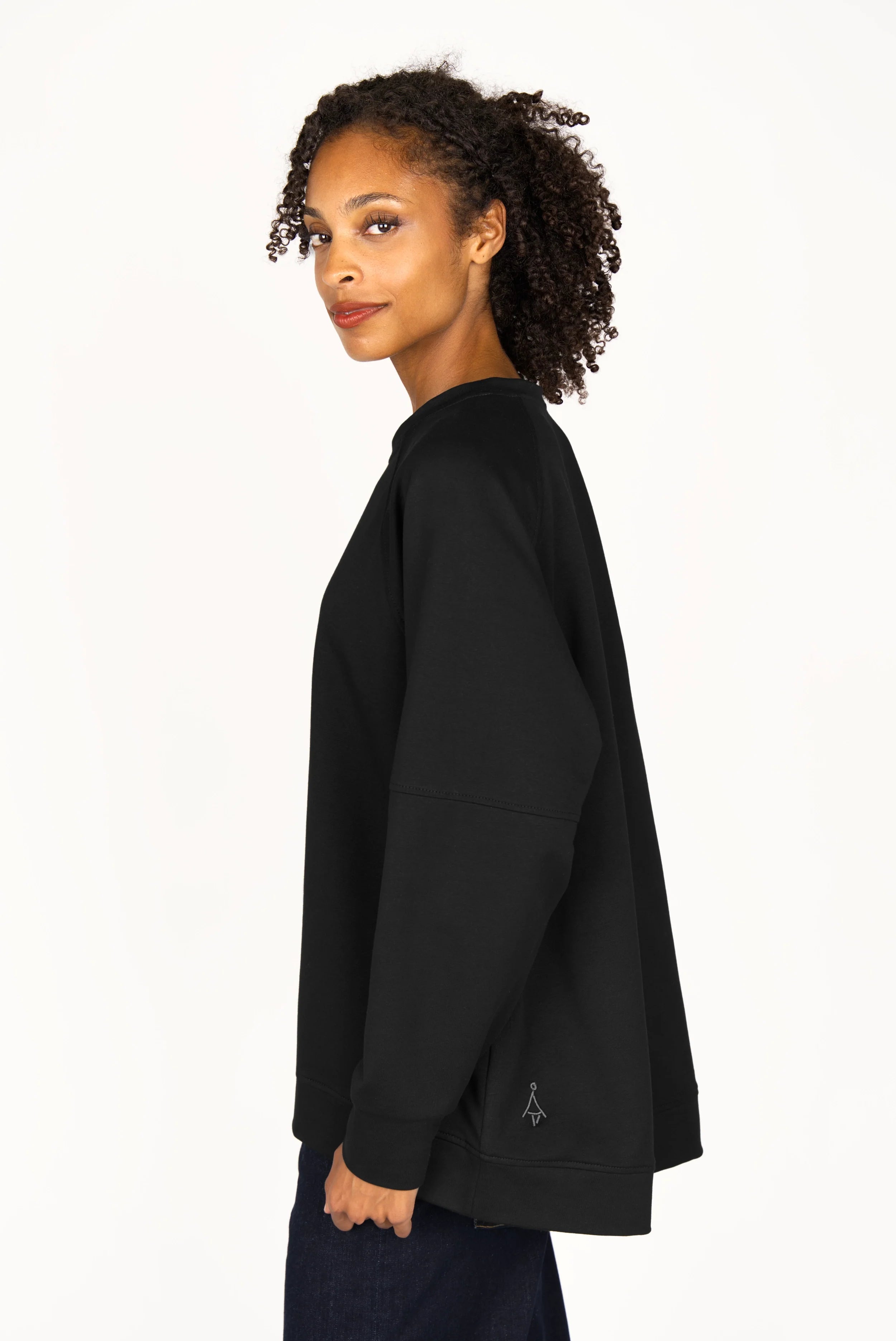 Black SELKA Sweater with A-line silhouette, raglan sleeves, and longer back hem on female model