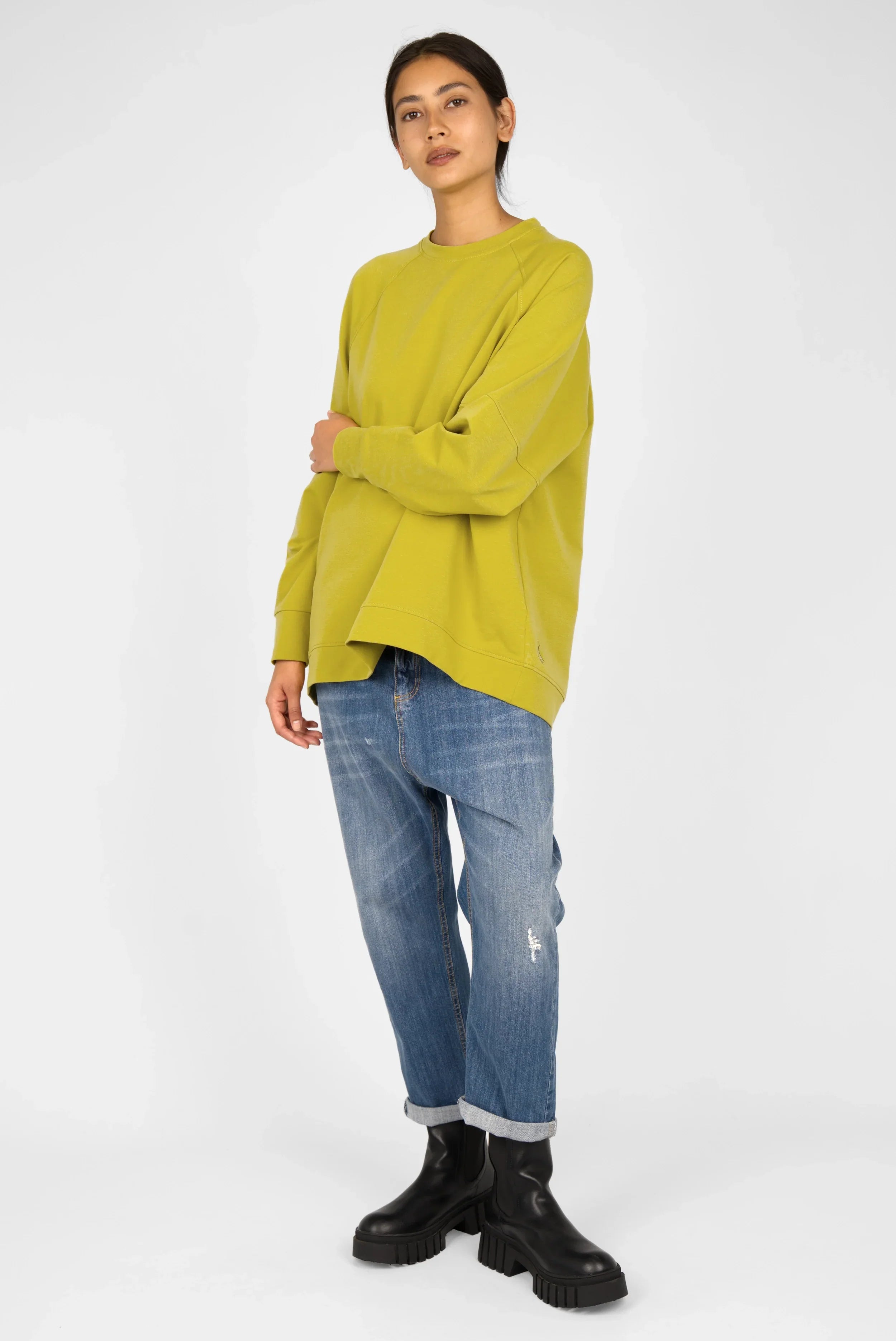 Model wearing green Selka Sweater with A-line relaxed fit, raglan sleeves, and longer back hem.