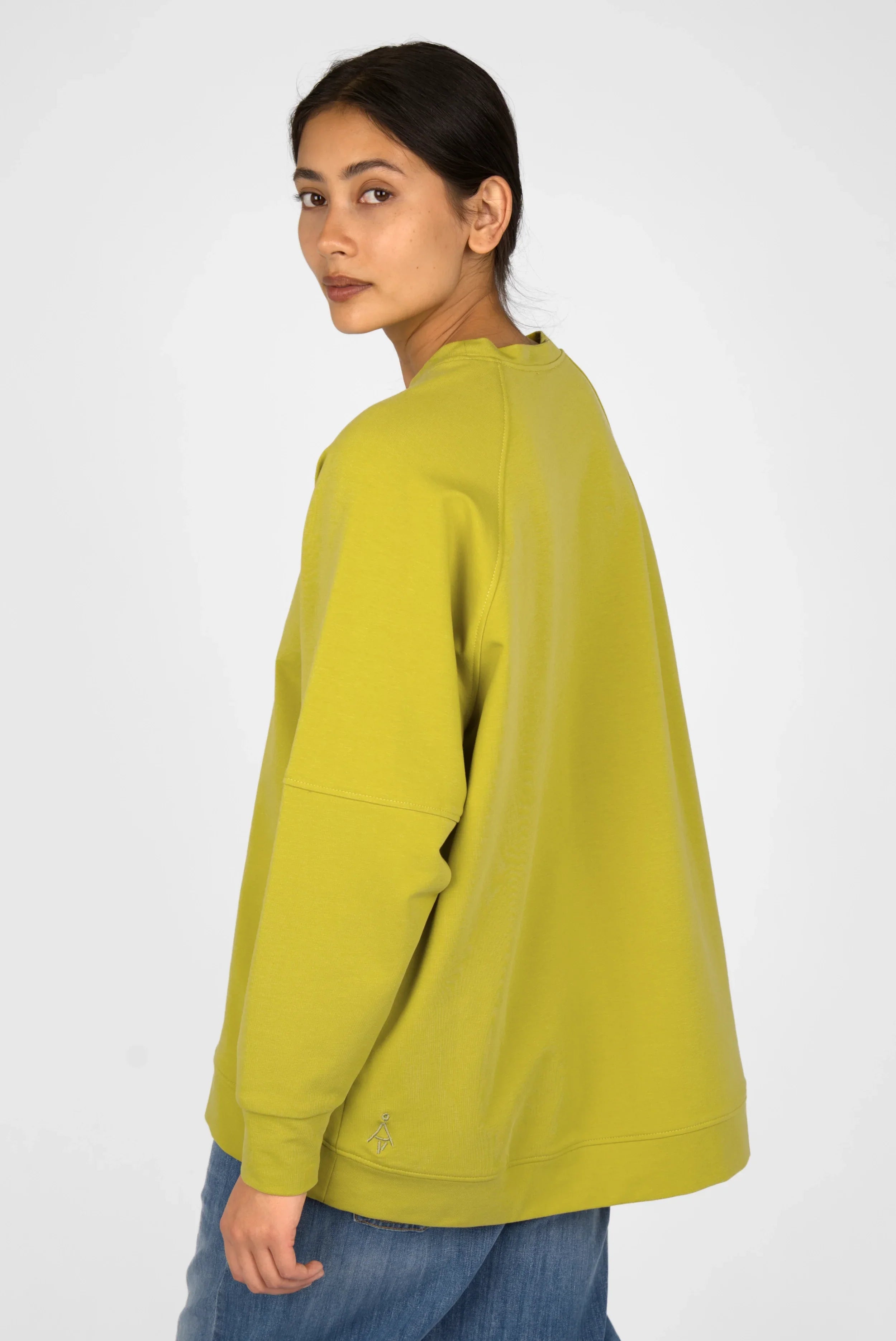 Woman wearing green oversized Selka Sweater with raglan sleeves and longer back hem