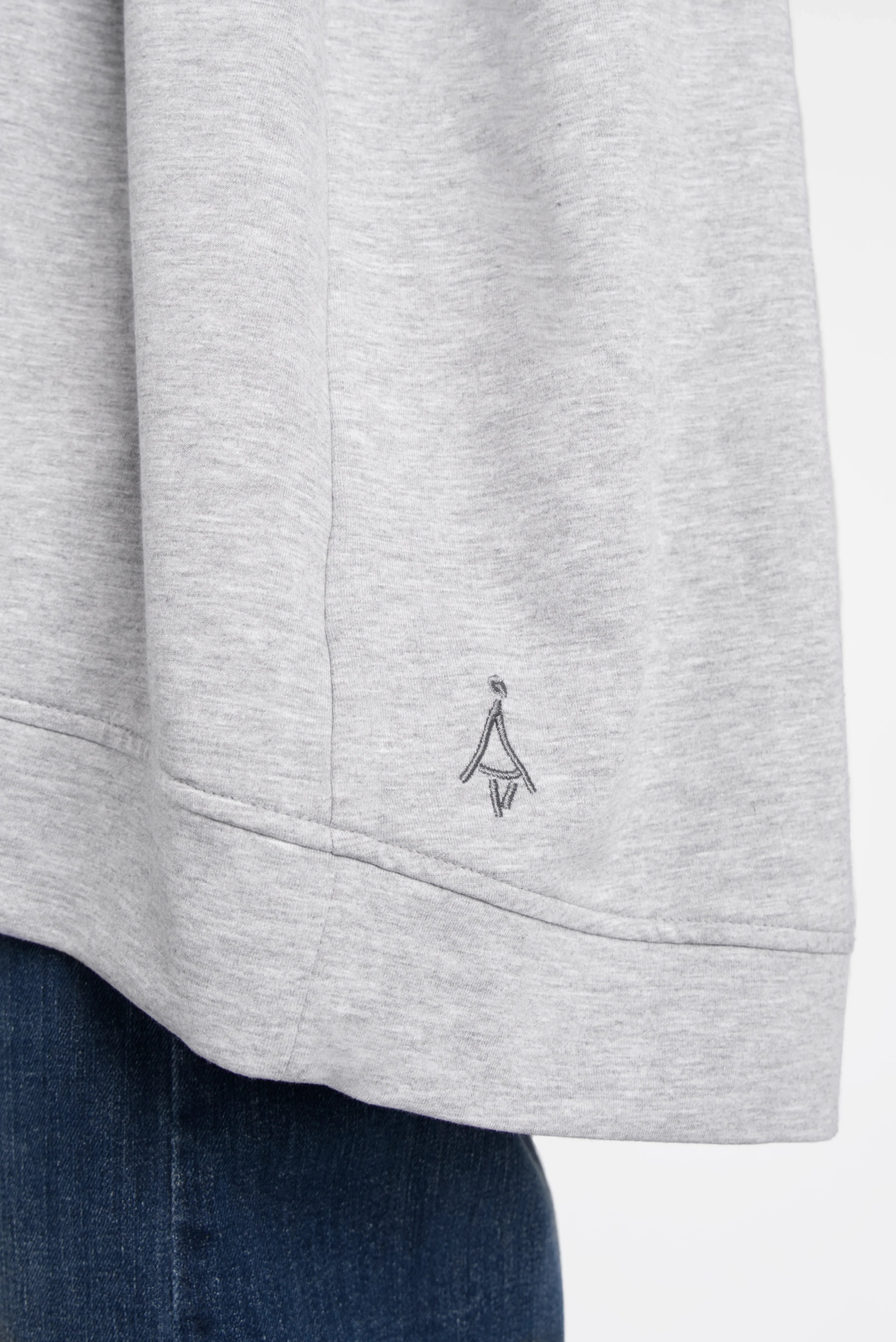 Close-up of light grey SELKA Sweater hem with tonal logo embroidery and rounded back longer cut.