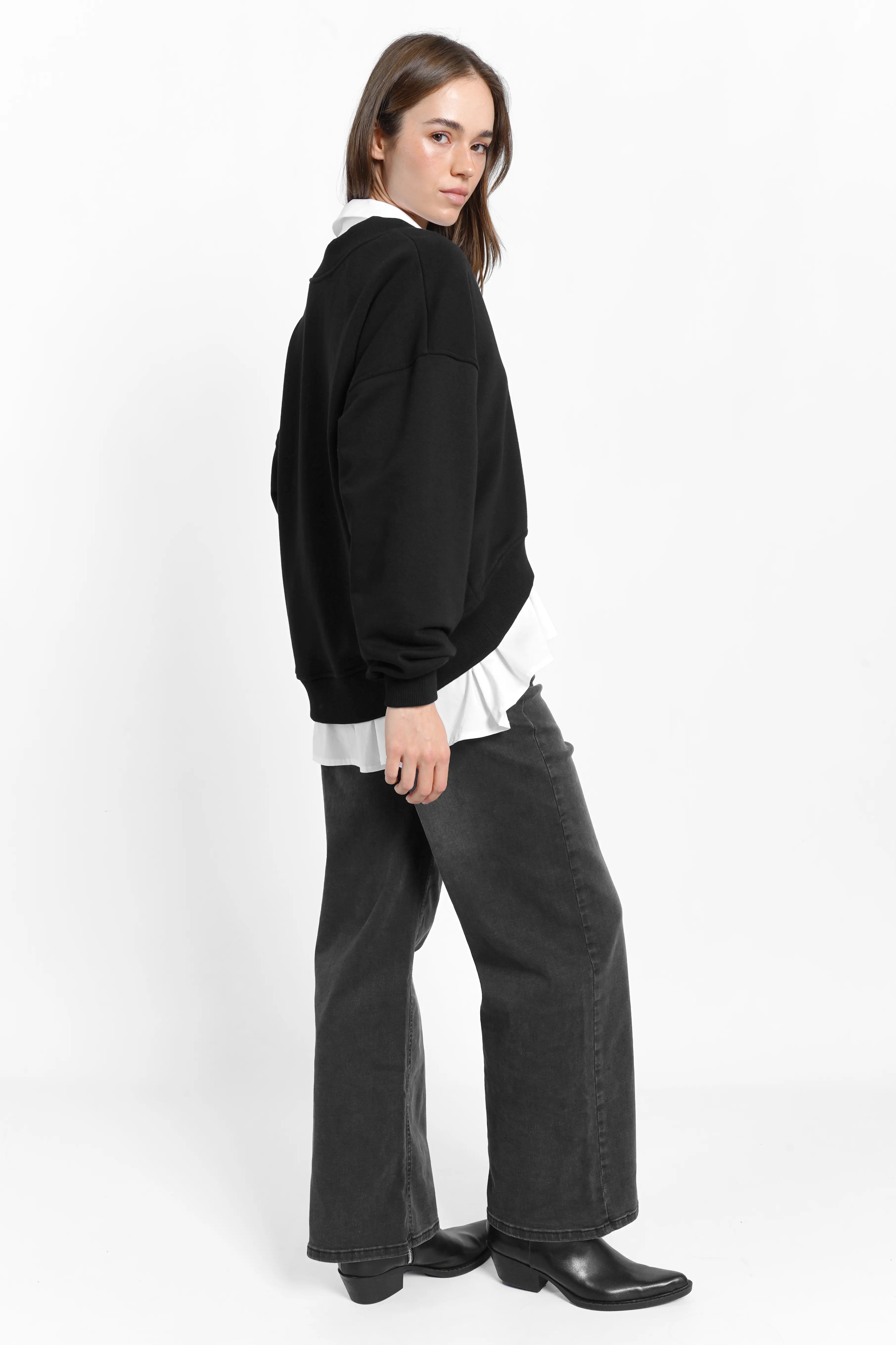 Damen trägt schwarzen SEREA Sweater mit tiefem V-Ausschnitt und Rippbündchen, lässiger Passform und Raffdetail am Ärmel.