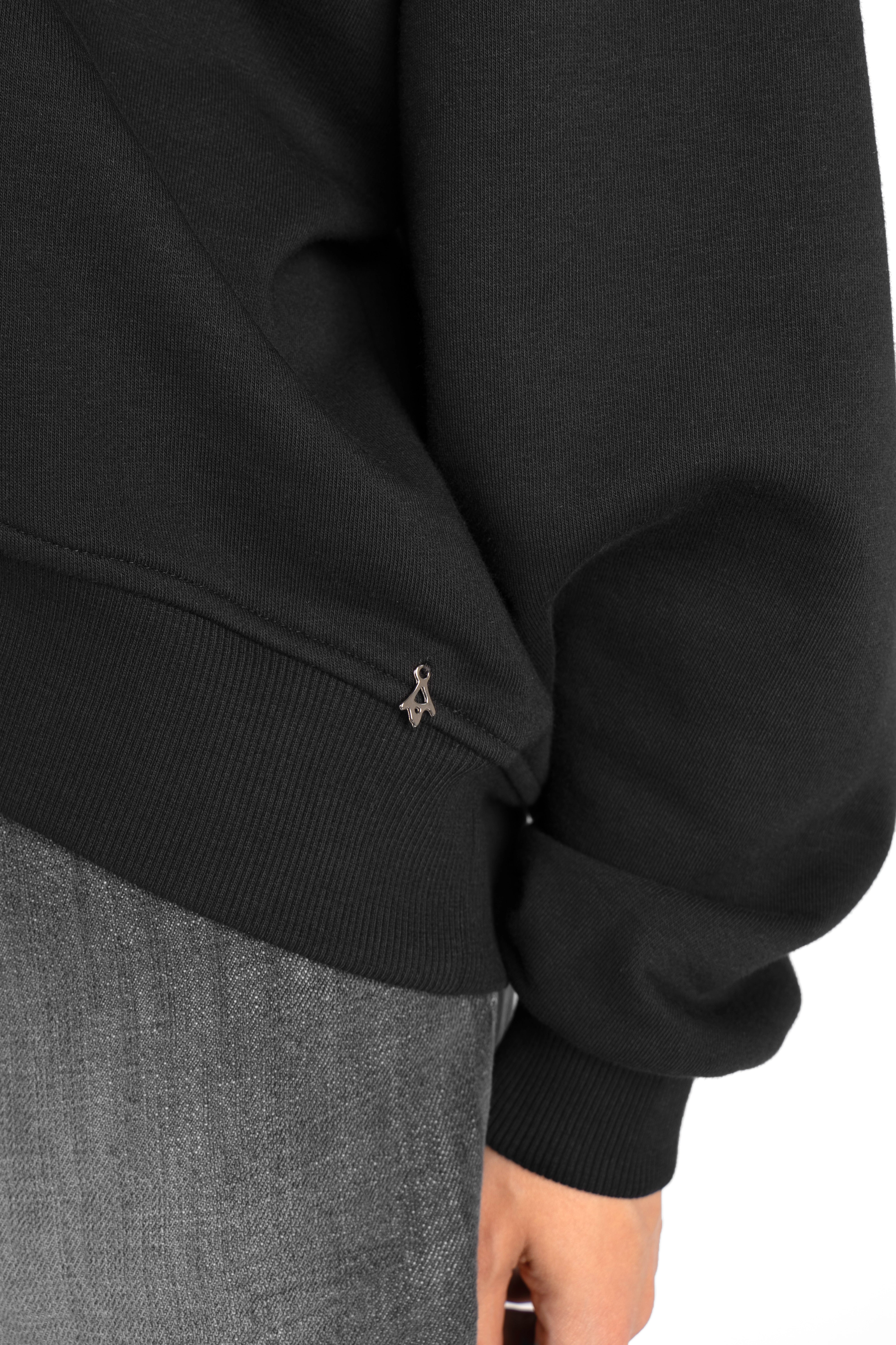 Close-up of black SEREA Sweater mit V-Ausschnitt with ribbed cuffs and shortened hem showing sleeve detail