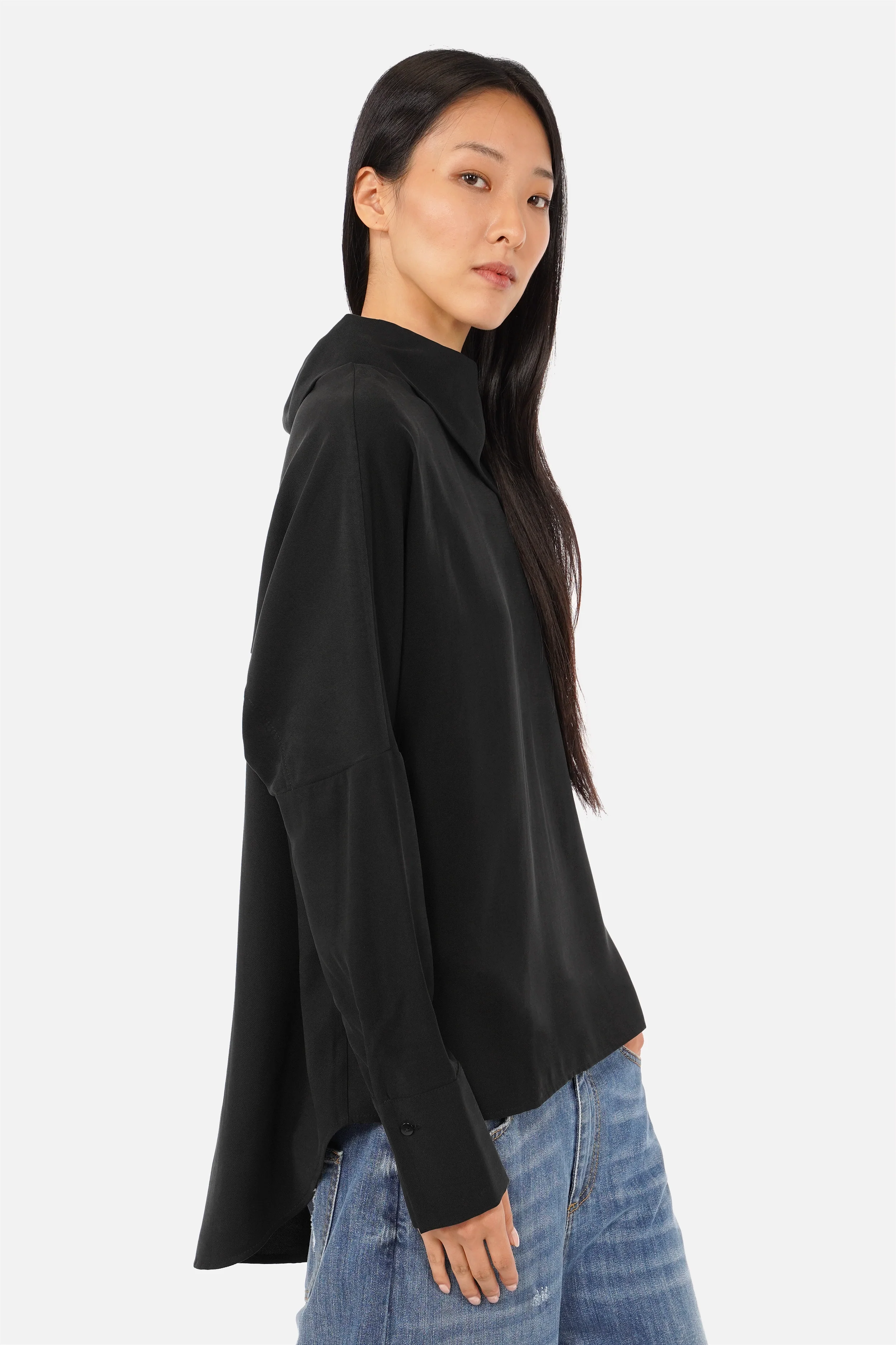 Damen trägt elegante One Shoulder Bluse aus leicht fallendem Lyocell mit asymmetrischem Kragen und Knopfleiste