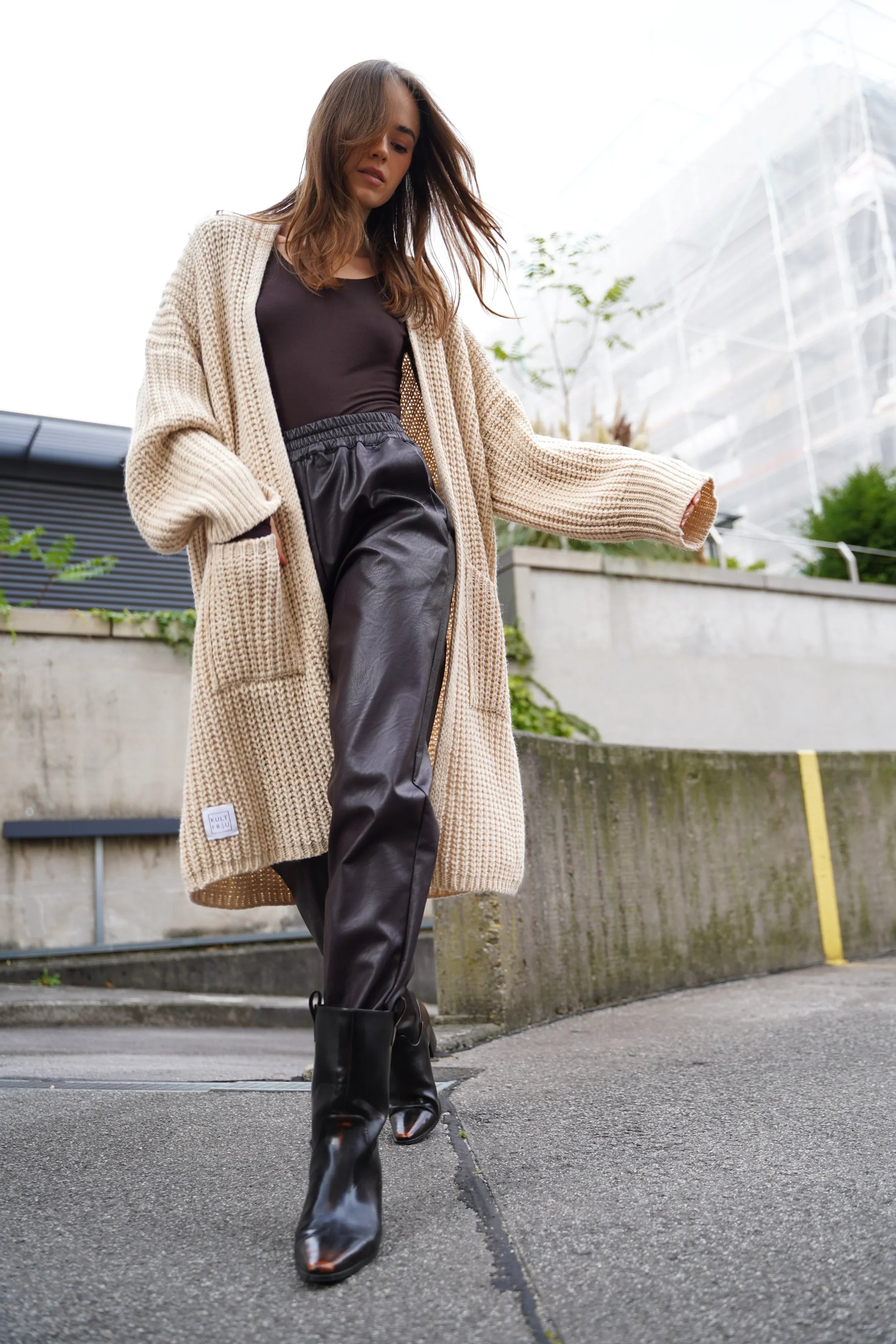 SOOMIN Jogpants in Lederoptik mit elastischem Bund und seitlichen Taschen, kombiniert mit beigem Cardigan und schwarzen Stiefeln