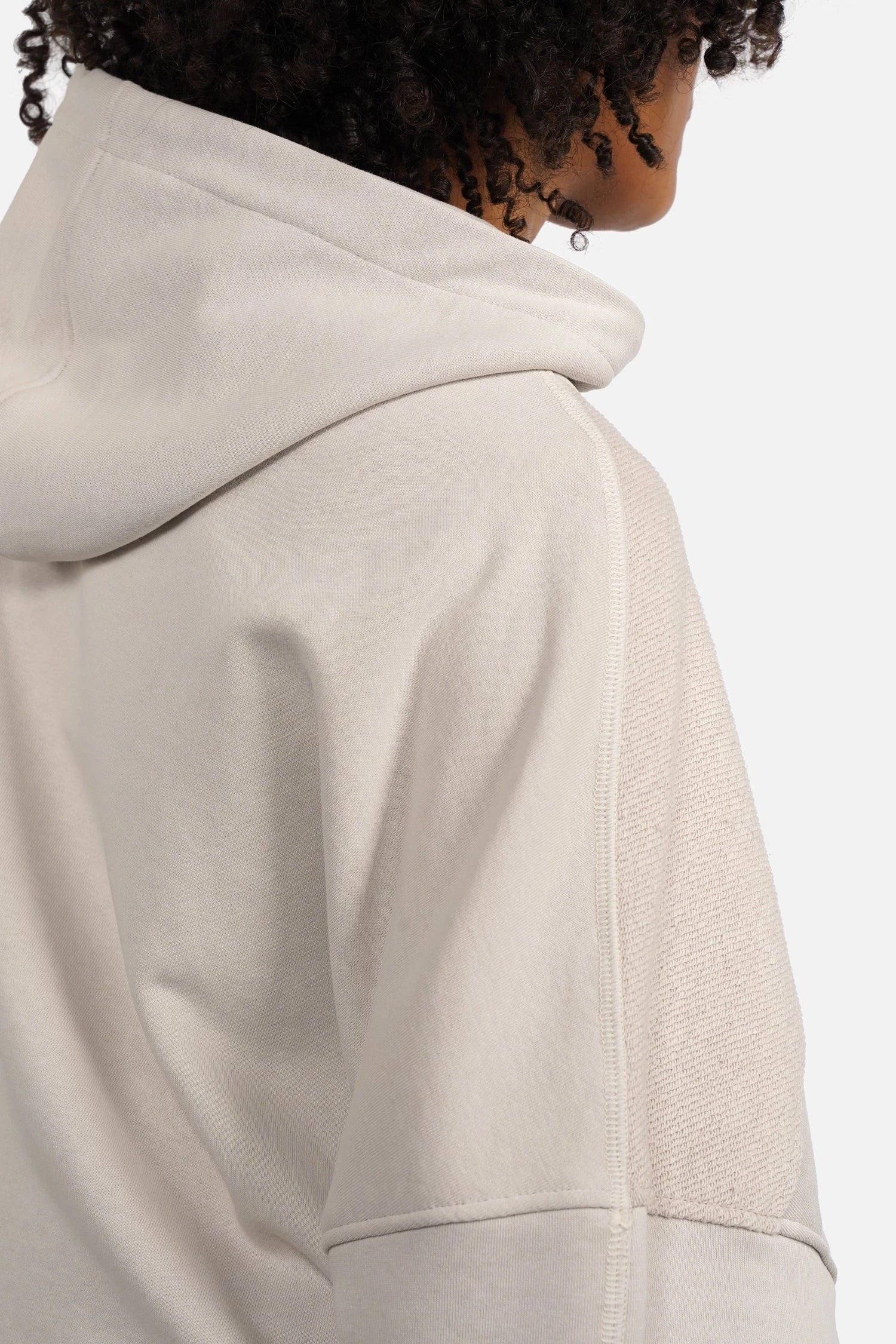 Oversized zip-hoodie with panel seams, pink logo zipper, hood, dropped shoulders, wide cuffs, side pockets, and longer back hem