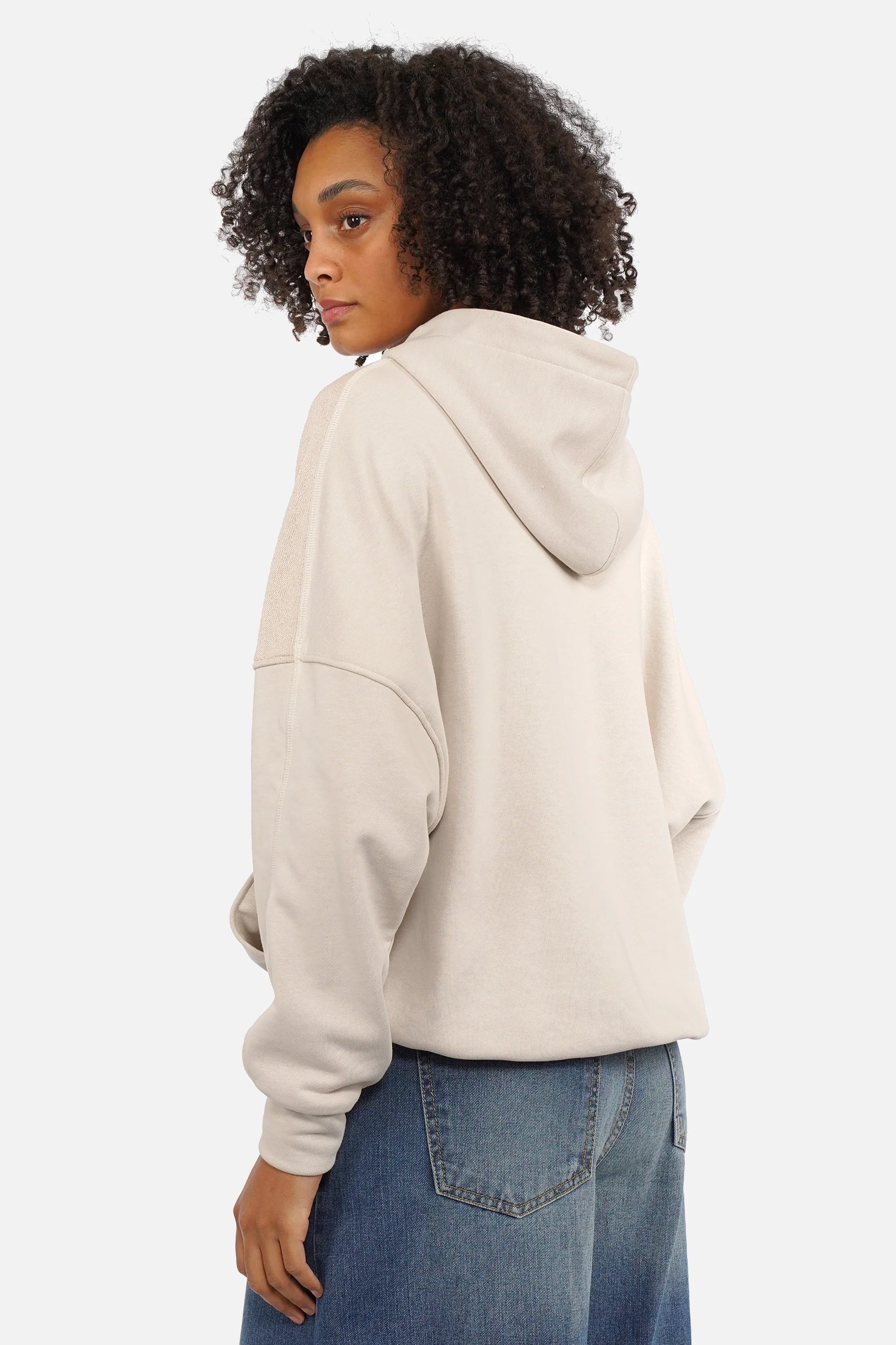 Oversized zip-hoodie with panel seams, pink logo zipper, hood, dropped shoulders, wide cuffs, side pockets, elastic hem, longer back, worn by model.