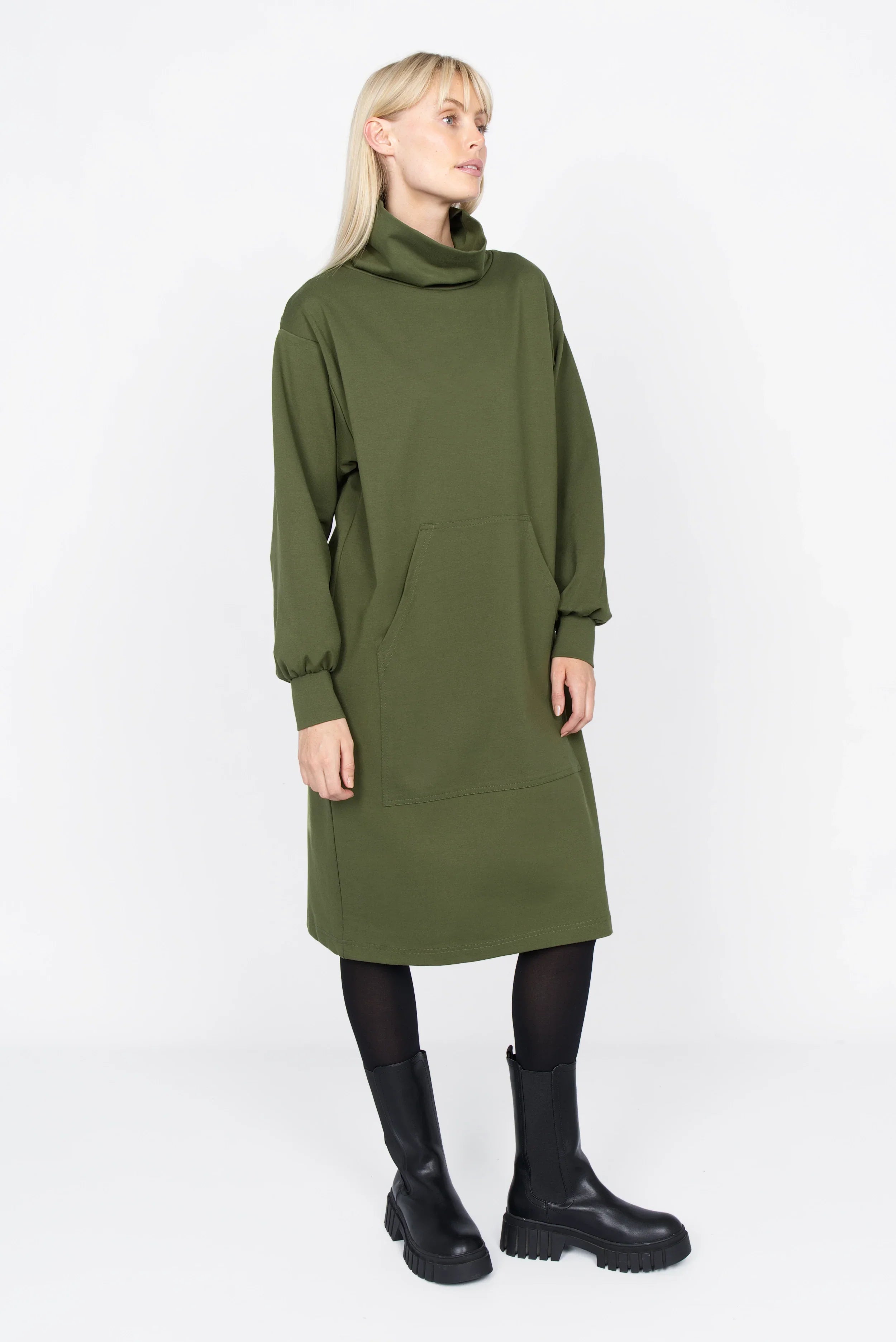 Frau trägt SYNNI Kleid aus grünem Viskose-Jersey mit Stehkragen und Kängurutasche