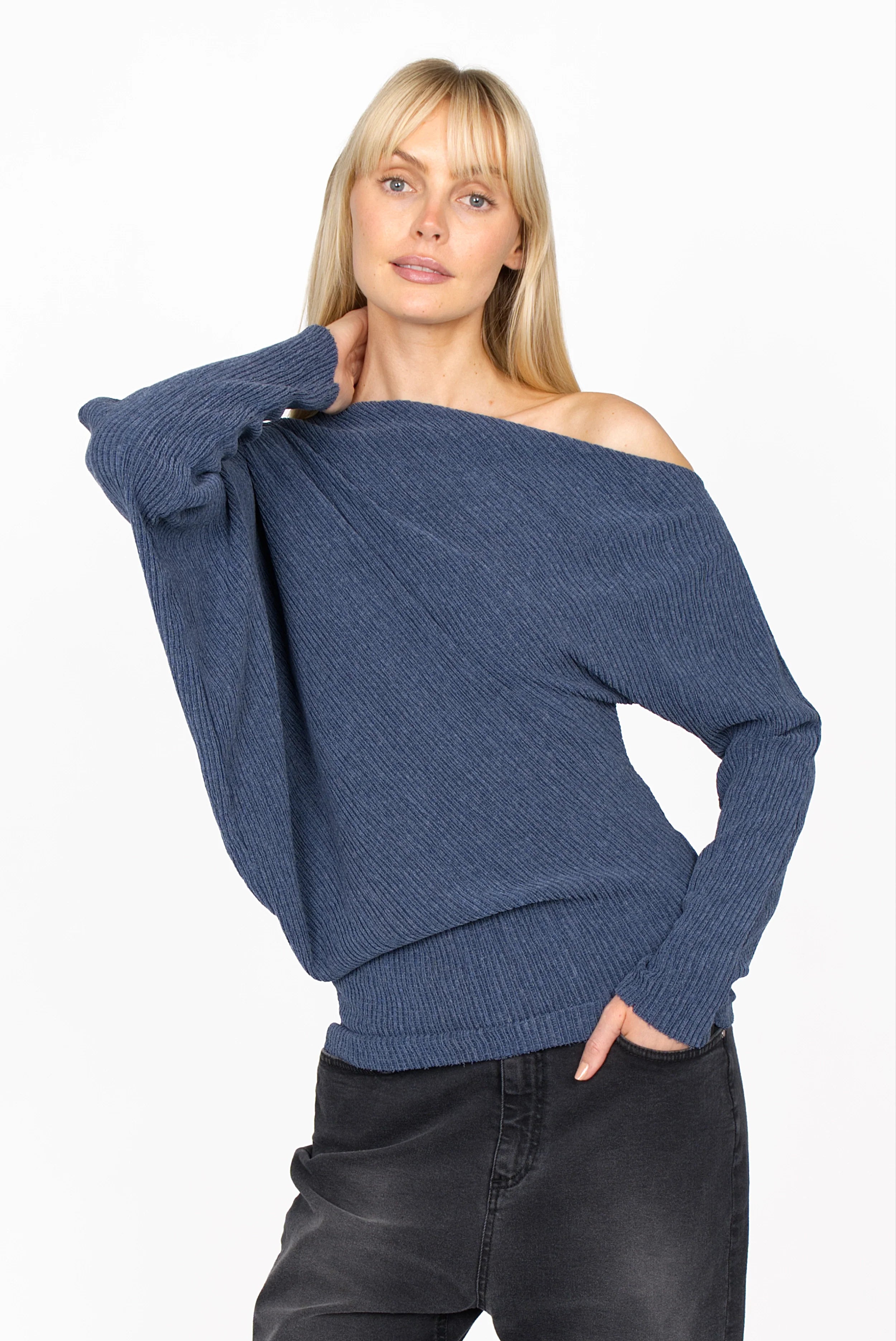 Woman wearing blue one-shoulder top with wide batwing sleeve and raw-cut hem