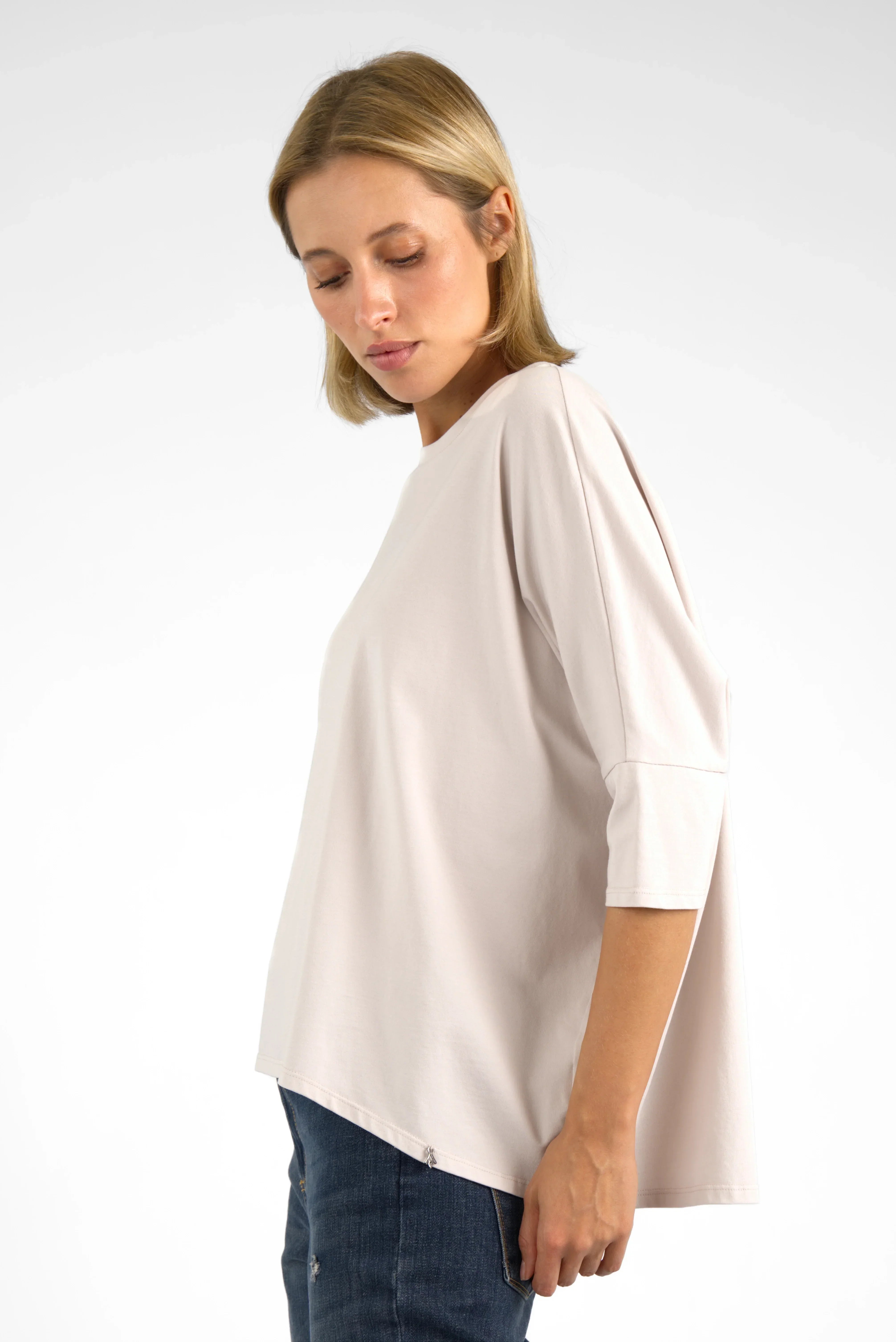 Woman wearing beige TAMI.K Blusenshirt with relaxed fit and rounded hem standing against white background