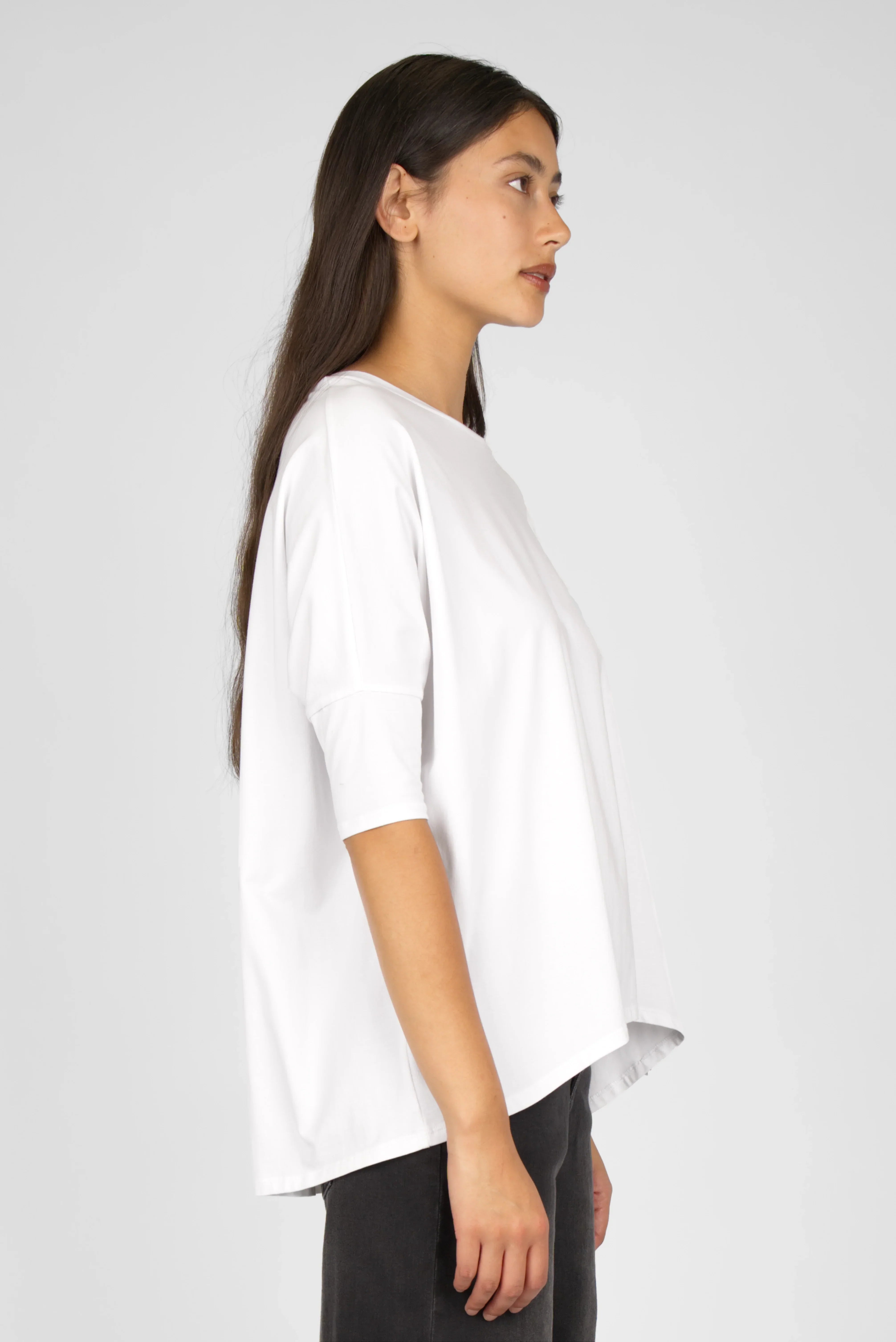 Side view of a woman wearing a white TAMI.K Blusenshirt with relaxed fit and round neck made of soft, breathable cotton