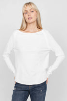 Damen trägt weißes TEHI Longsleeve aus softer Fiammato Baumwolle mit Rundhalsausschnitt und extralangen Raglanärmeln in Regular Fit