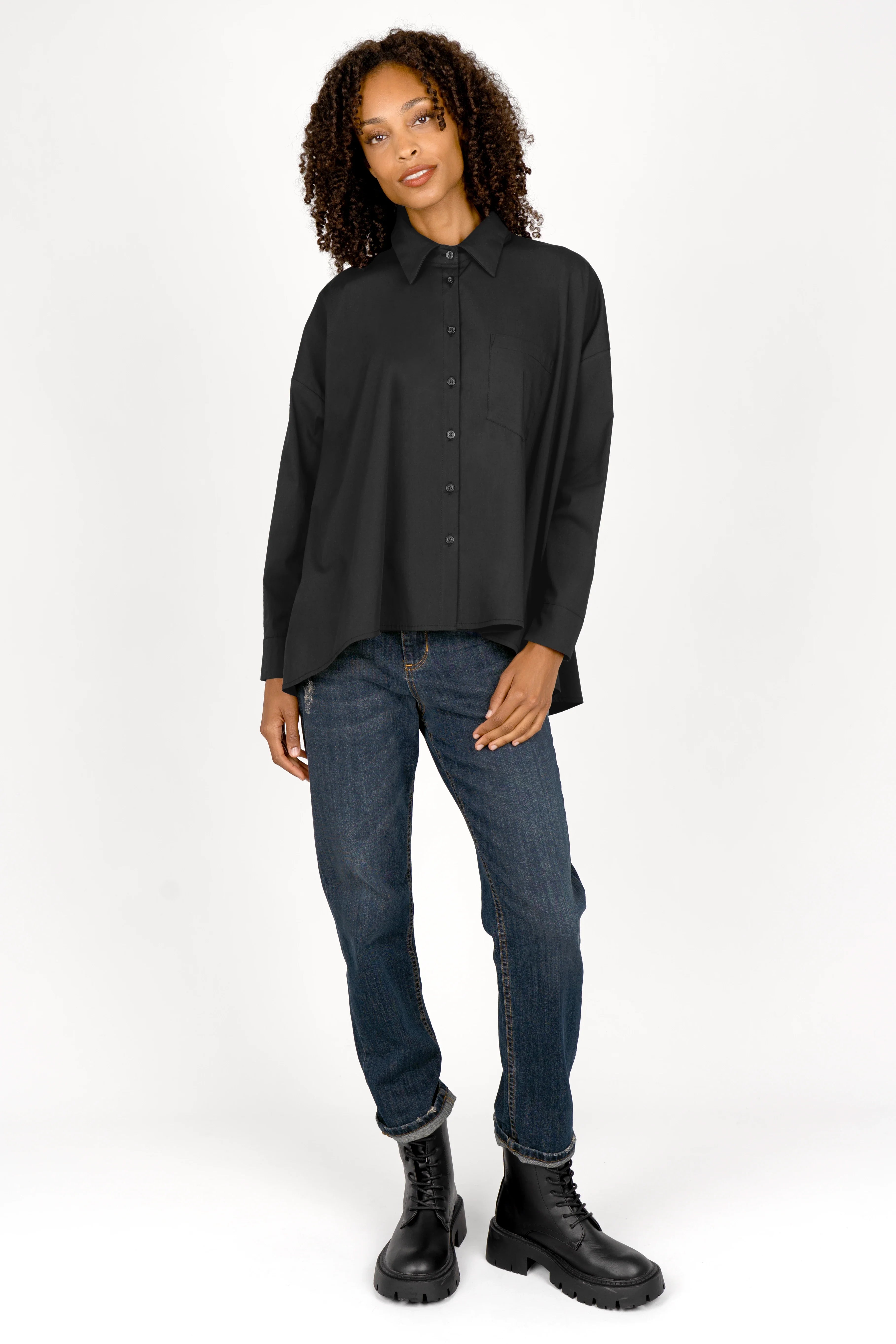 Woman wearing black oversized Bluse with button-down front, classic collar, and relaxed fit paired with jeans and black boots