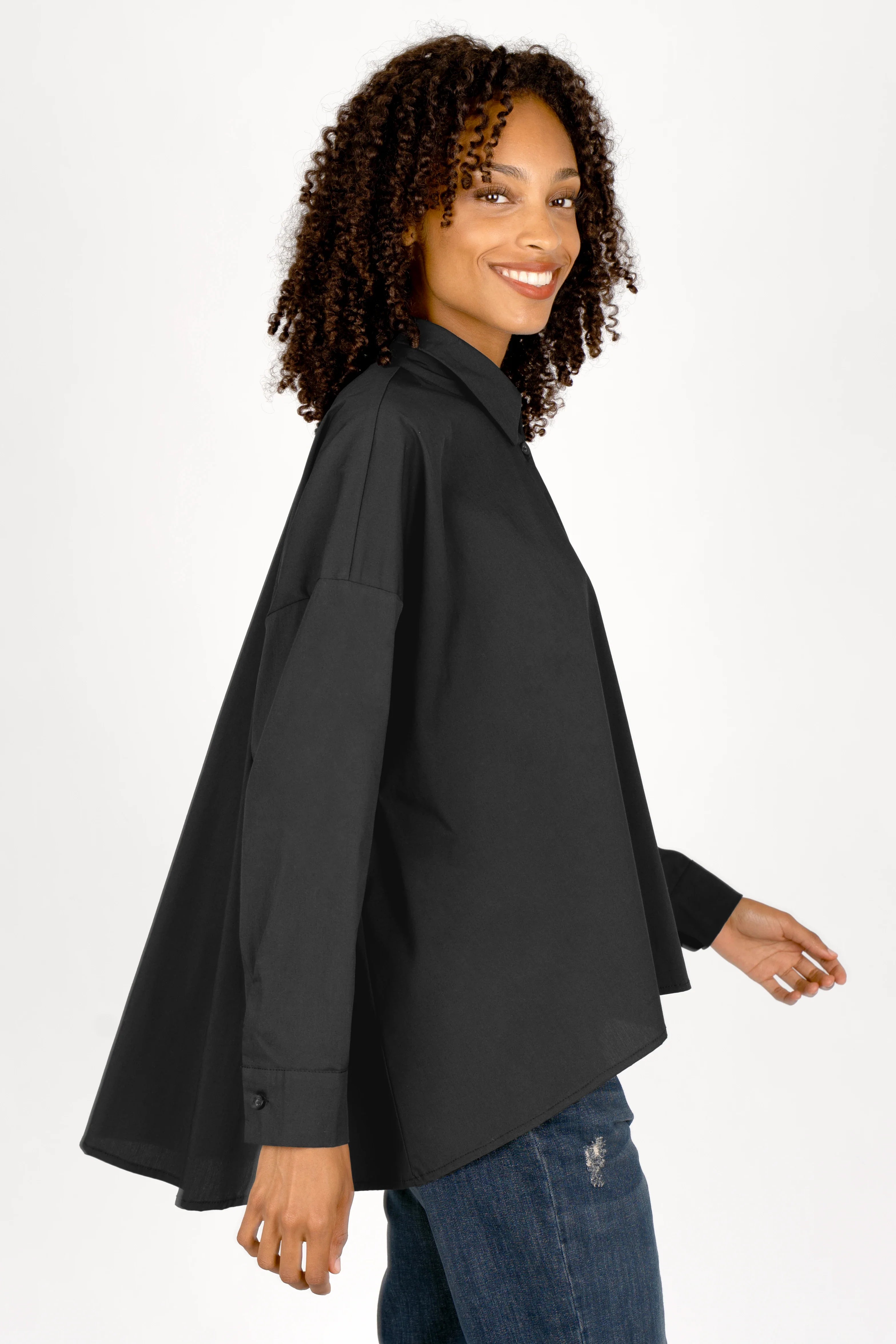 Woman wearing black oversized Bluse with classic collar and dropped shoulders, made of smooth poplin fabric with A-line silhouette and button cuffs